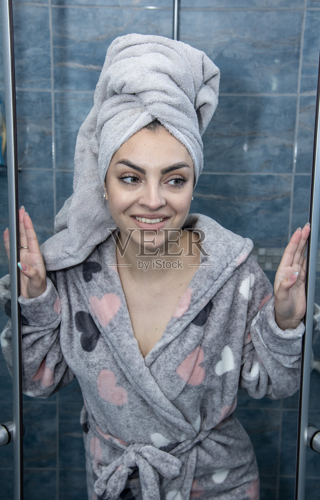 女孩在浴室里用毛巾在她的头上享受她的水疗日。照片摄影图片