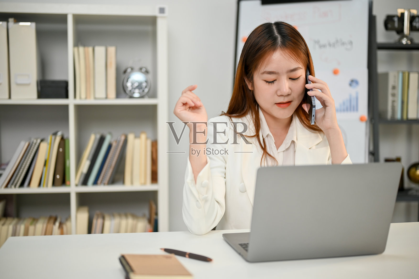 一位专注的亚洲商人正在和她的商业伙伴打电话，谈生意照片摄影图片