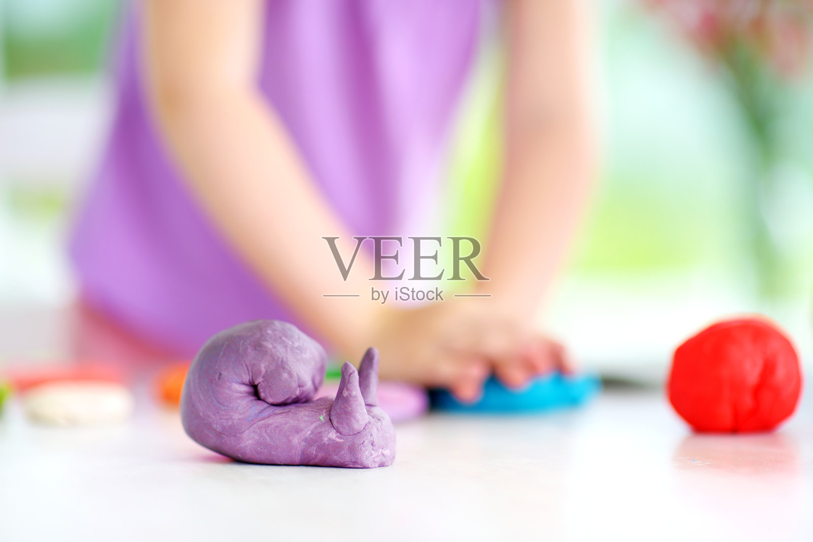 可爱的小女孩在日托所玩黏土模型。创造性的孩子在家里塑造。照片摄影图片