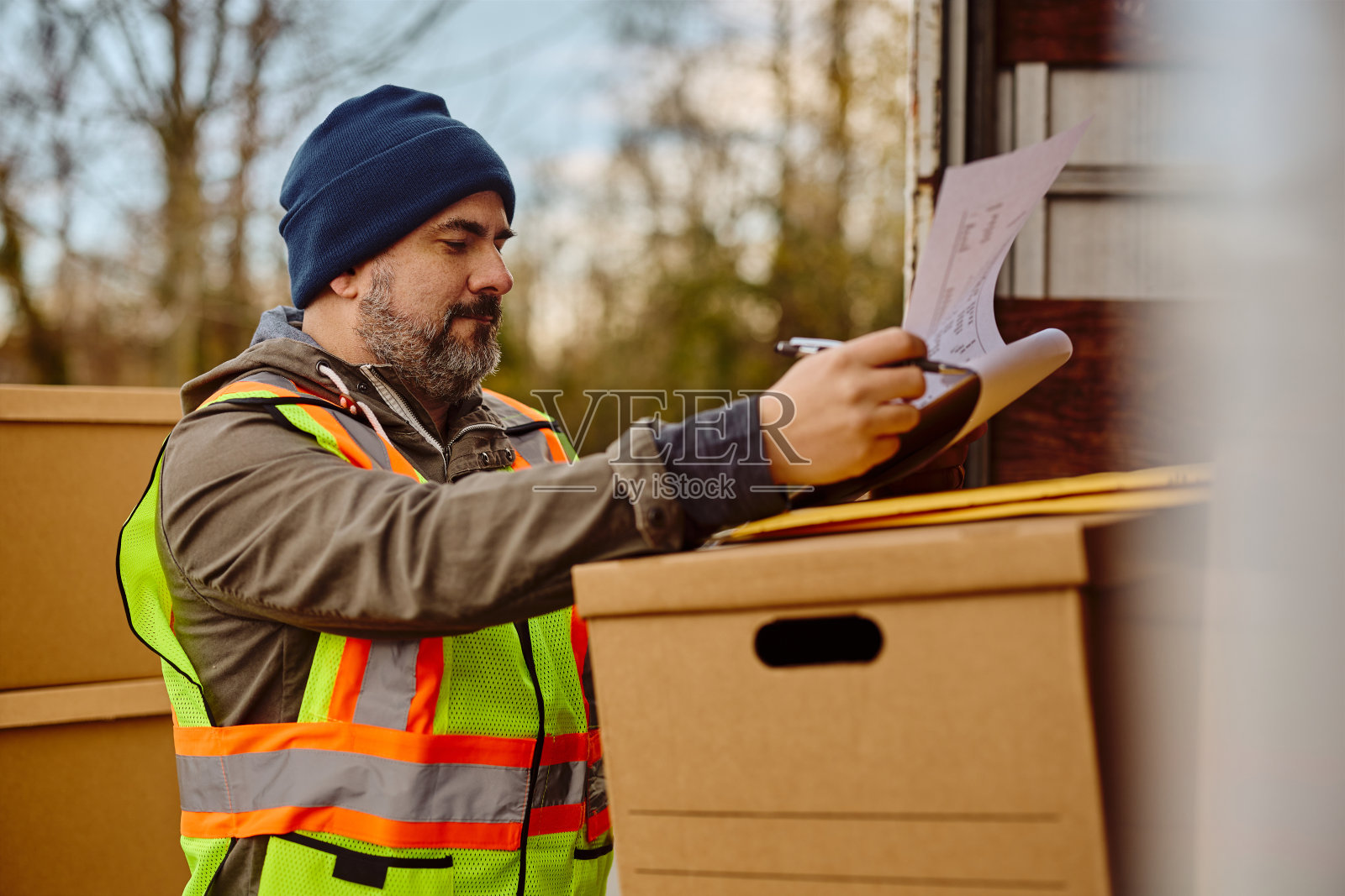 卡车司机检查货物清单，同时准备乘车。照片摄影图片