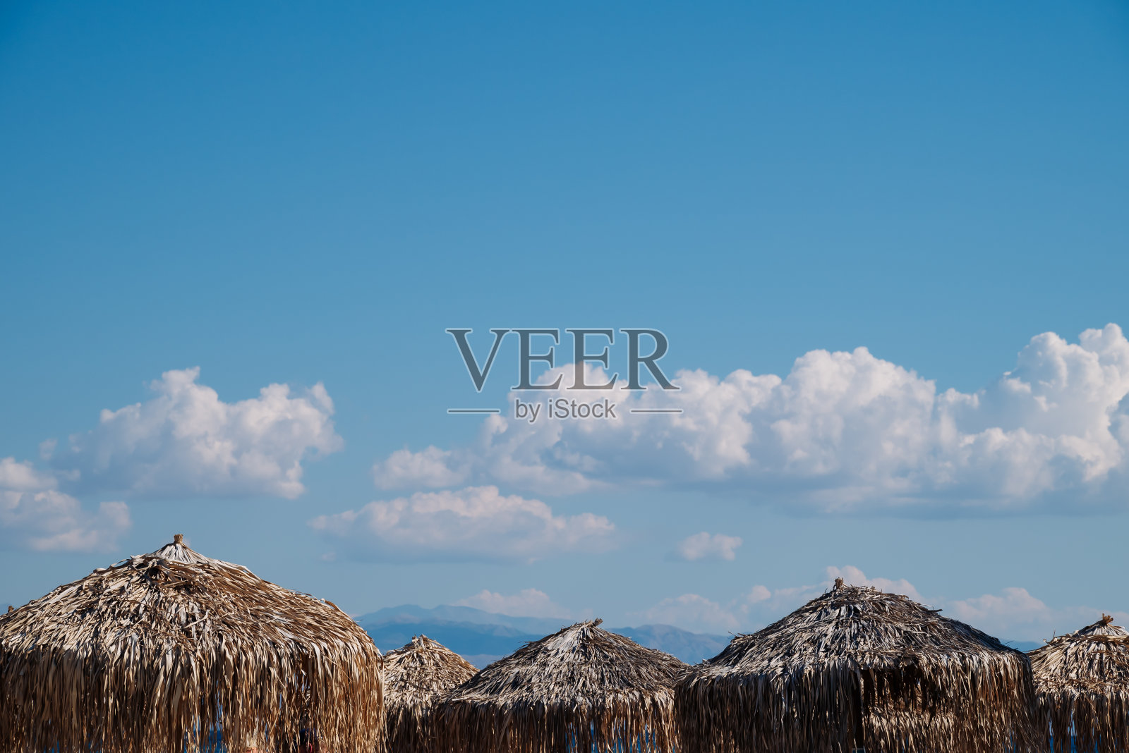 在希腊科孚岛的Moraitika，沙滩伞由棕榈叶制成，背景是蓝天。高质量照片照片摄影图片