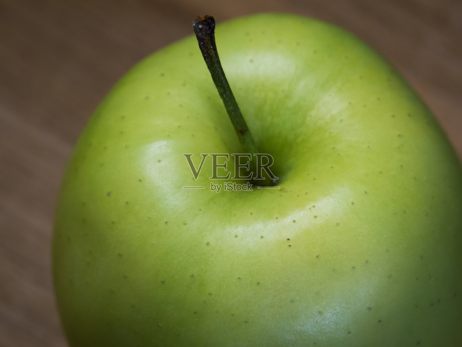 Reinette Simirenko是一个古老的苹果品种。这种水果有嫩、脆、绿色的白色果肉，带有亚酸味。一个绿苹果放在木桌上，特写。照片摄影图片