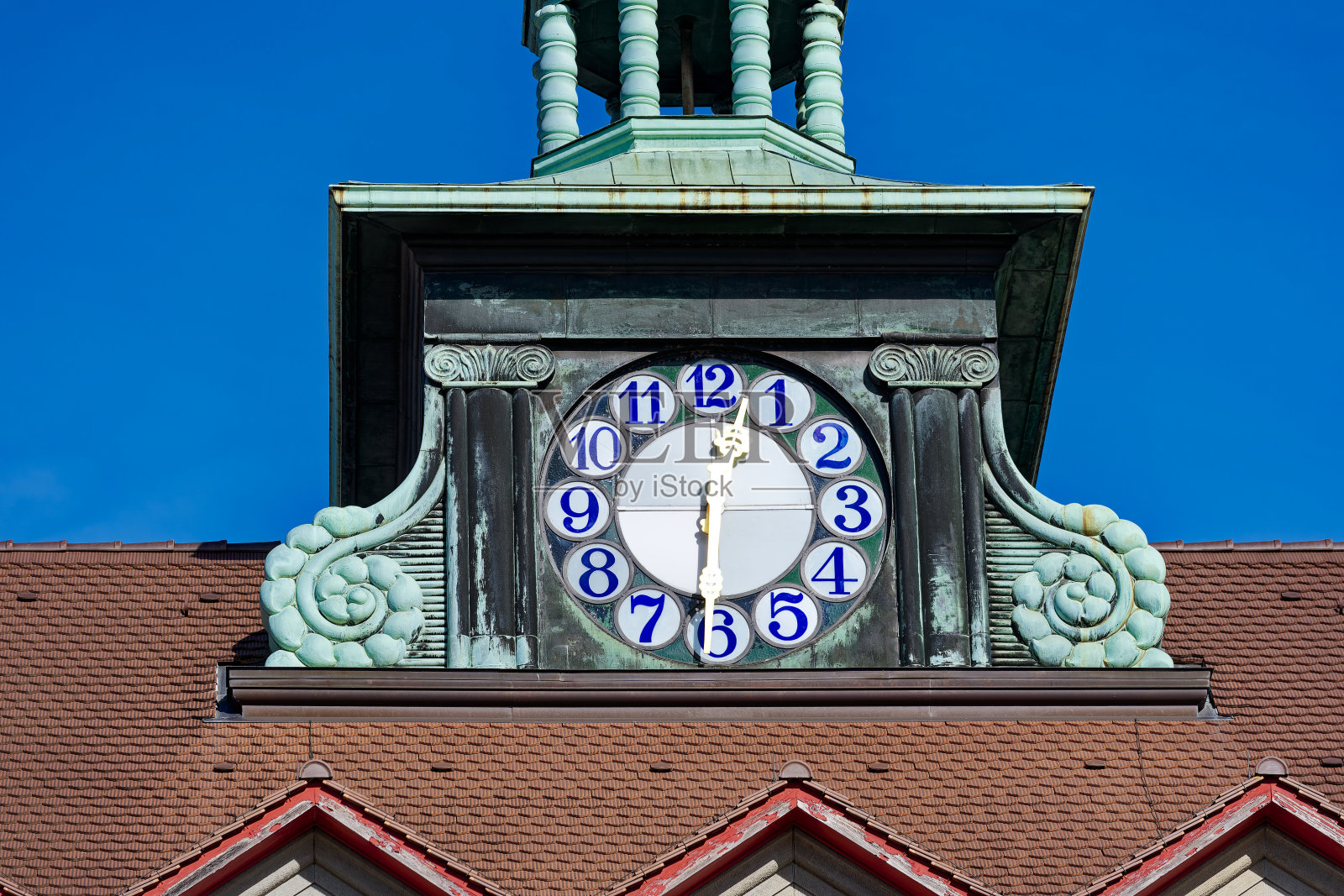 在一个阳光明媚的冬日，建筑物顶部的时钟显示12点半的时间。照片摄影图片