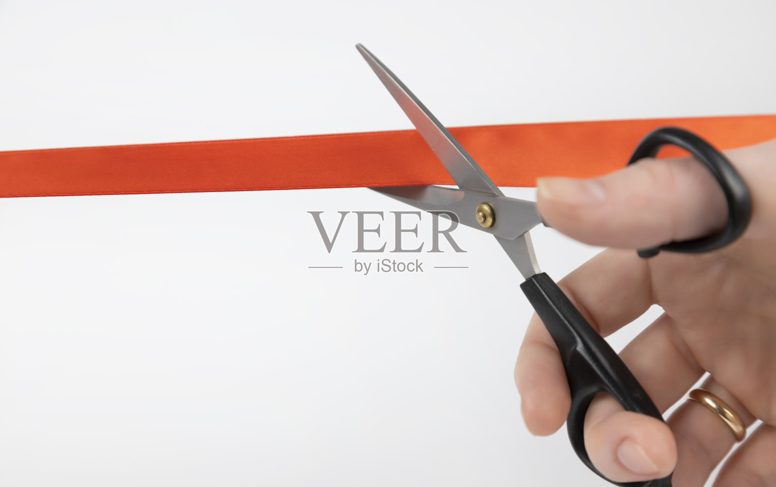 剪红丝带。一个女人的手用剪刀剪红丝带的特写照片摄影图片