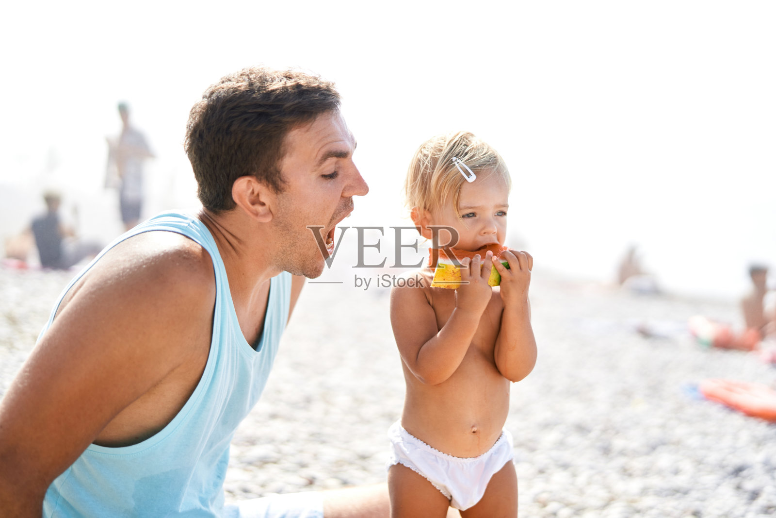 爸爸试着咬一块小女孩吃的西瓜照片摄影图片