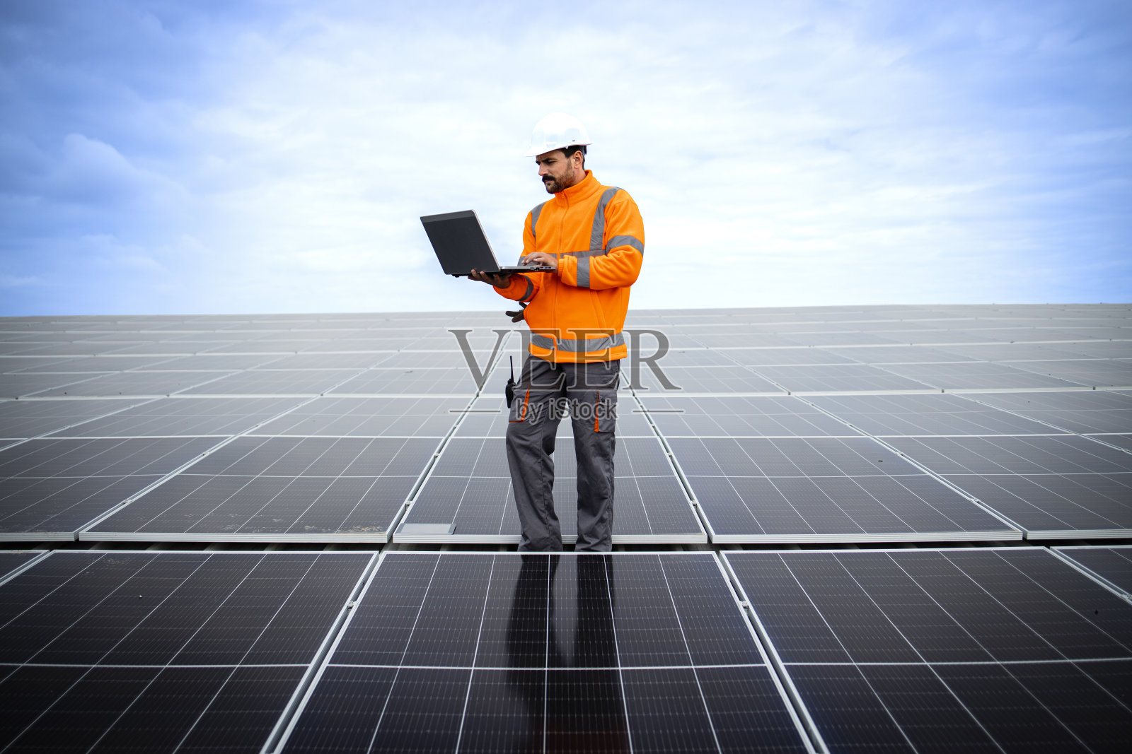 太阳能工程师手持笔记本电脑，检查发电厂的发电量。照片摄影图片