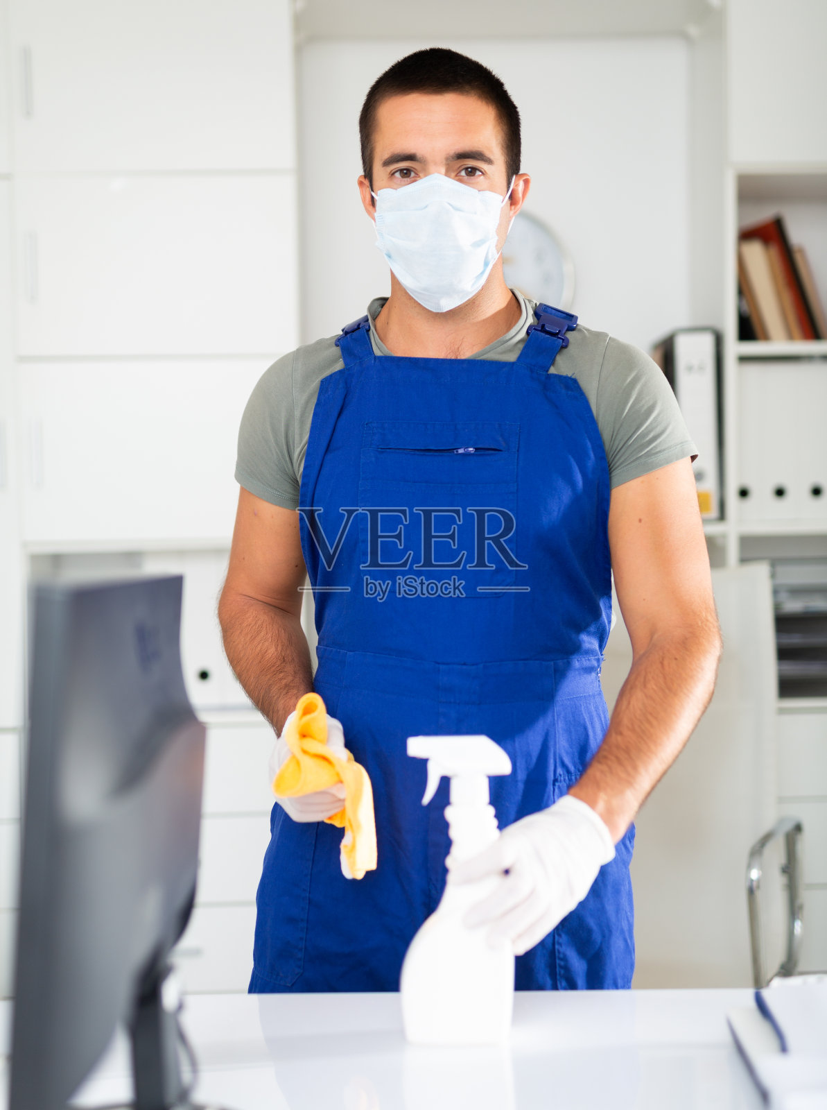戴着医用防护口罩的男清洁工在办公室打扫卫生照片摄影图片
