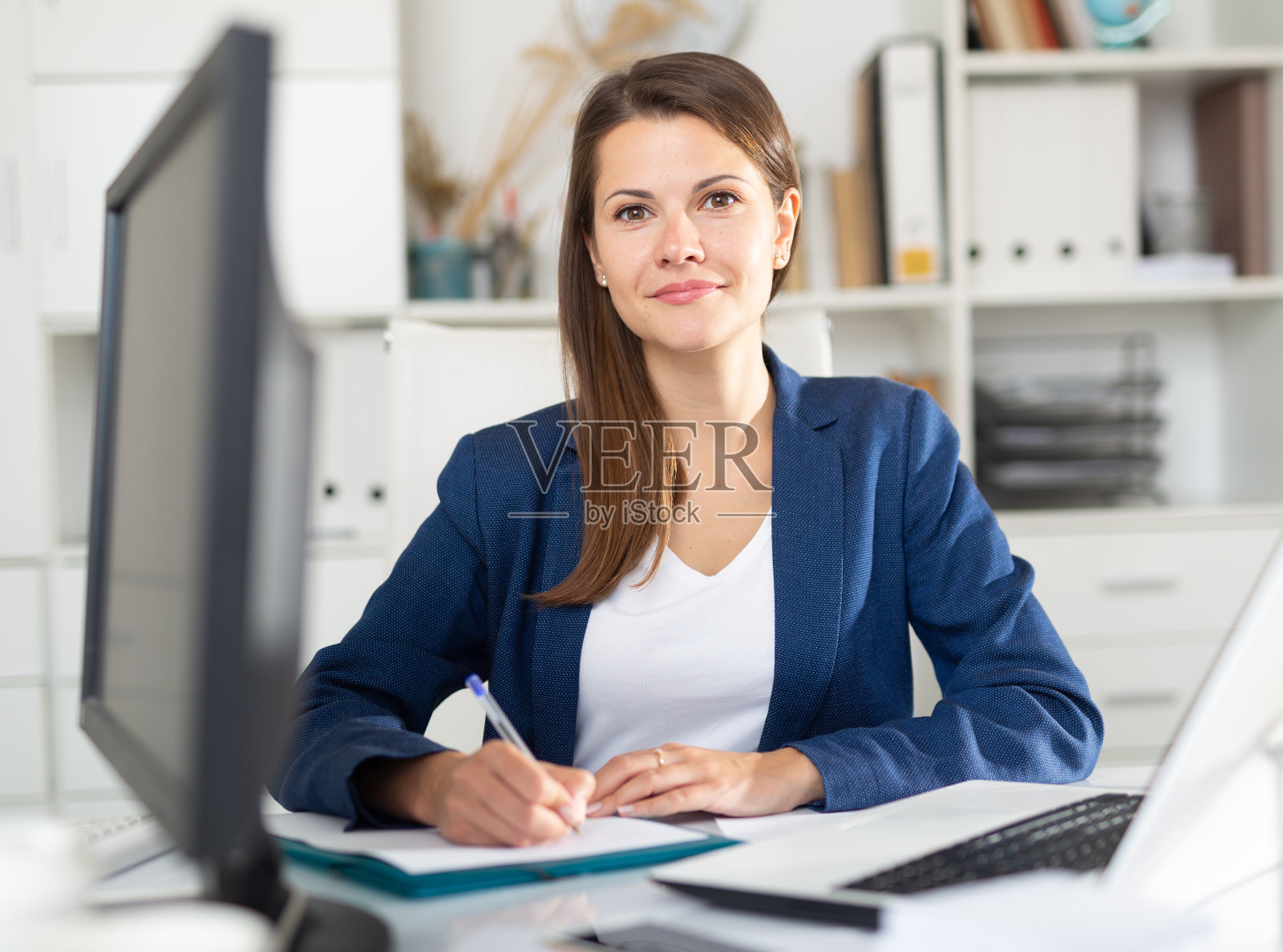 微笑的女人工作的文件和笔记本电脑照片摄影图片