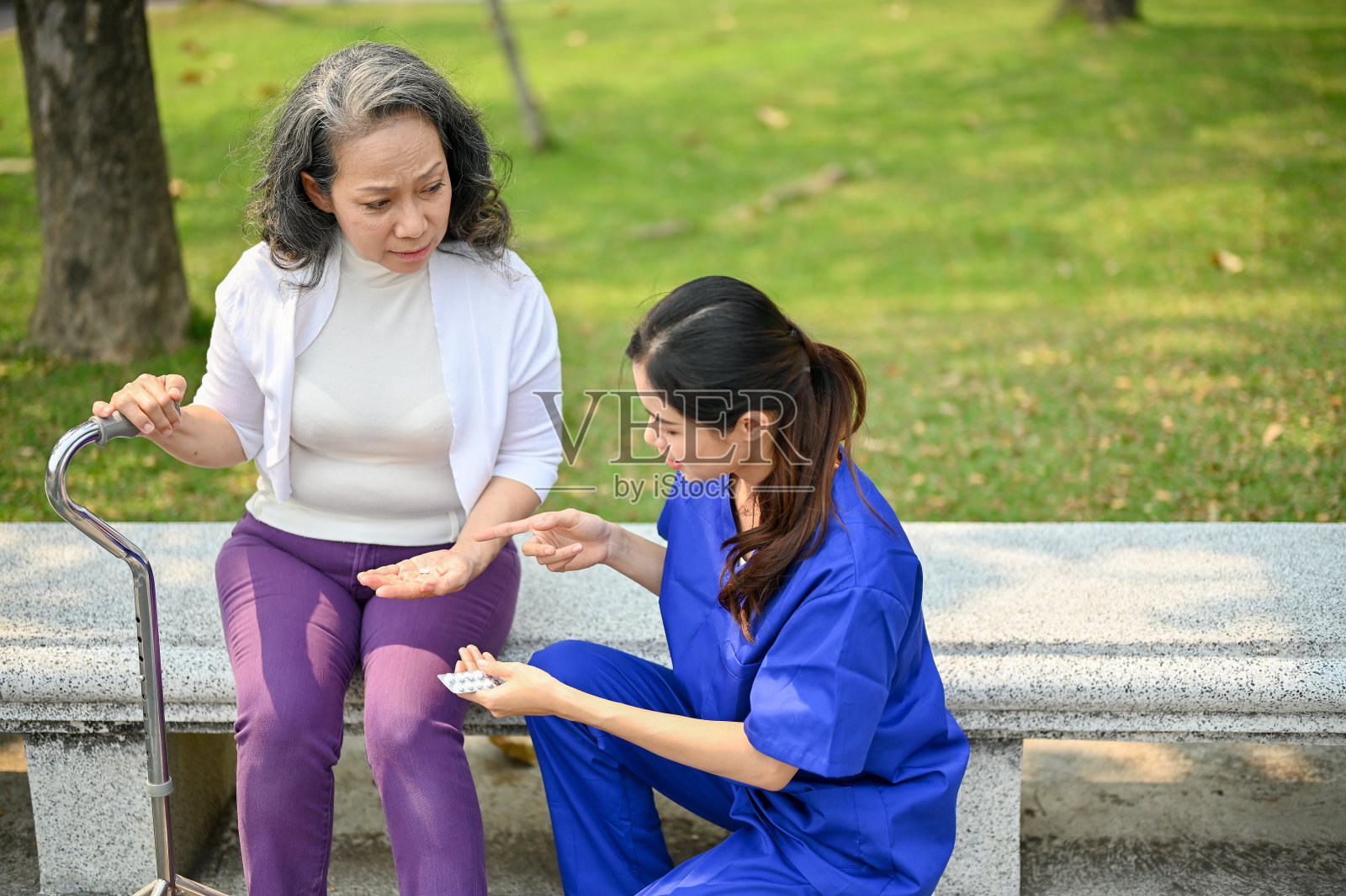 护理员向一位老妇病人解释药物剂量并给她药片照片摄影图片