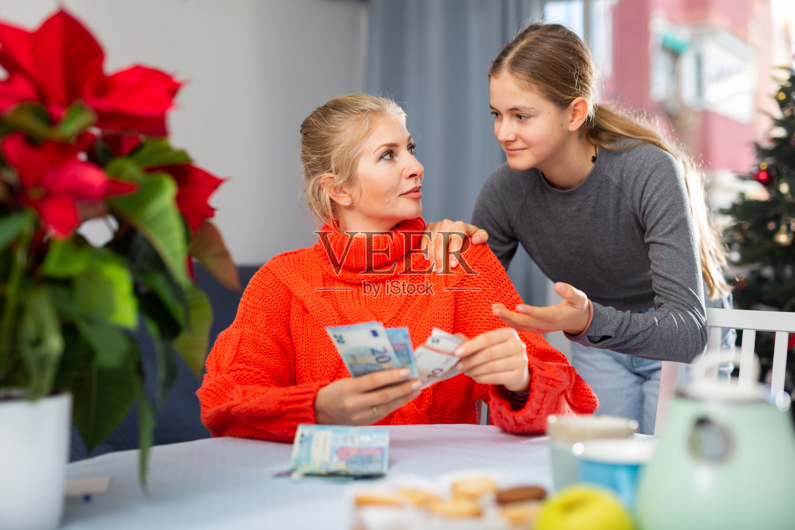 母亲给她十几岁的女儿零花钱照片摄影图片