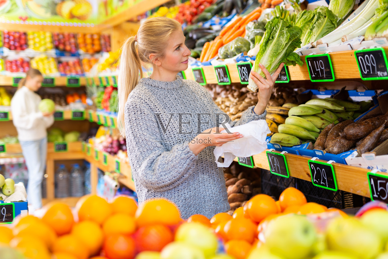 感兴趣的妇女在超市挑选新鲜的长叶莴苣照片摄影图片