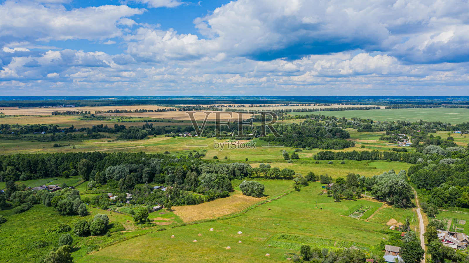在宽阔的山谷里俯瞰美丽的郊区，在夏天。鸟瞰小村庄，有美丽的绿色景观。照片摄影图片