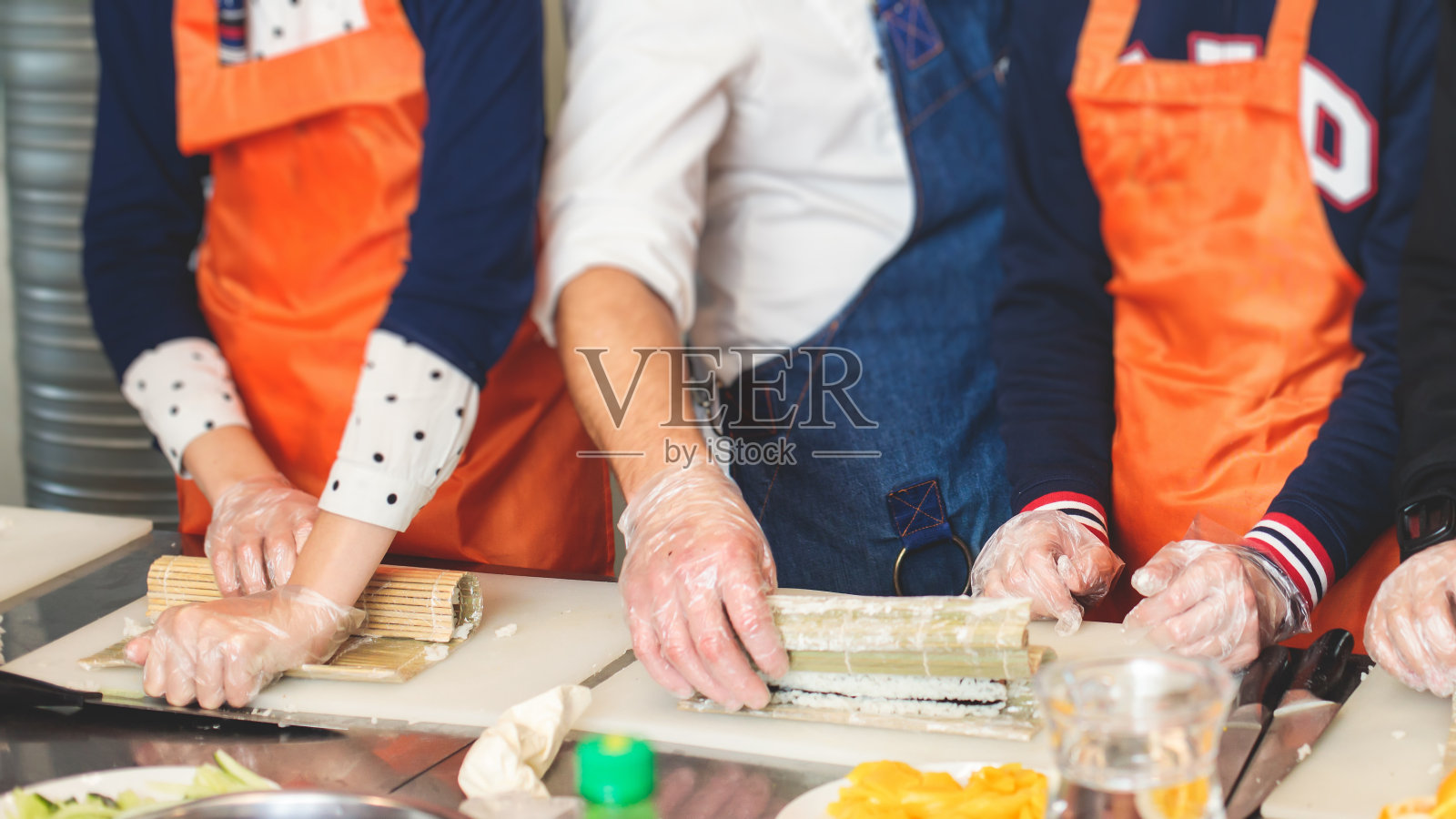 一群孩子在烹饪课上，孩子们一起在厨房准备亚洲风味的食物，孩子们穿着围裙在大师课上学习烹饪，厨师制服，手戴手套照片摄影图片
