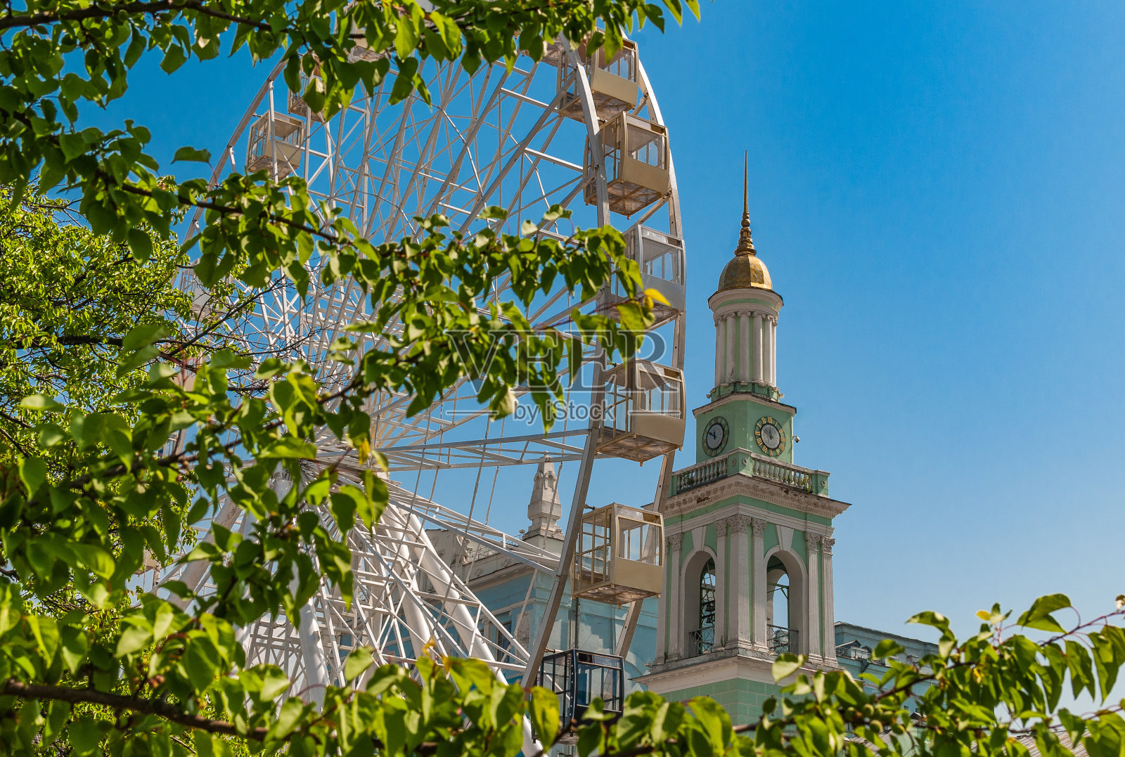 游乐园与摩天轮和绿色的树木在蓝天的背景照片摄影图片