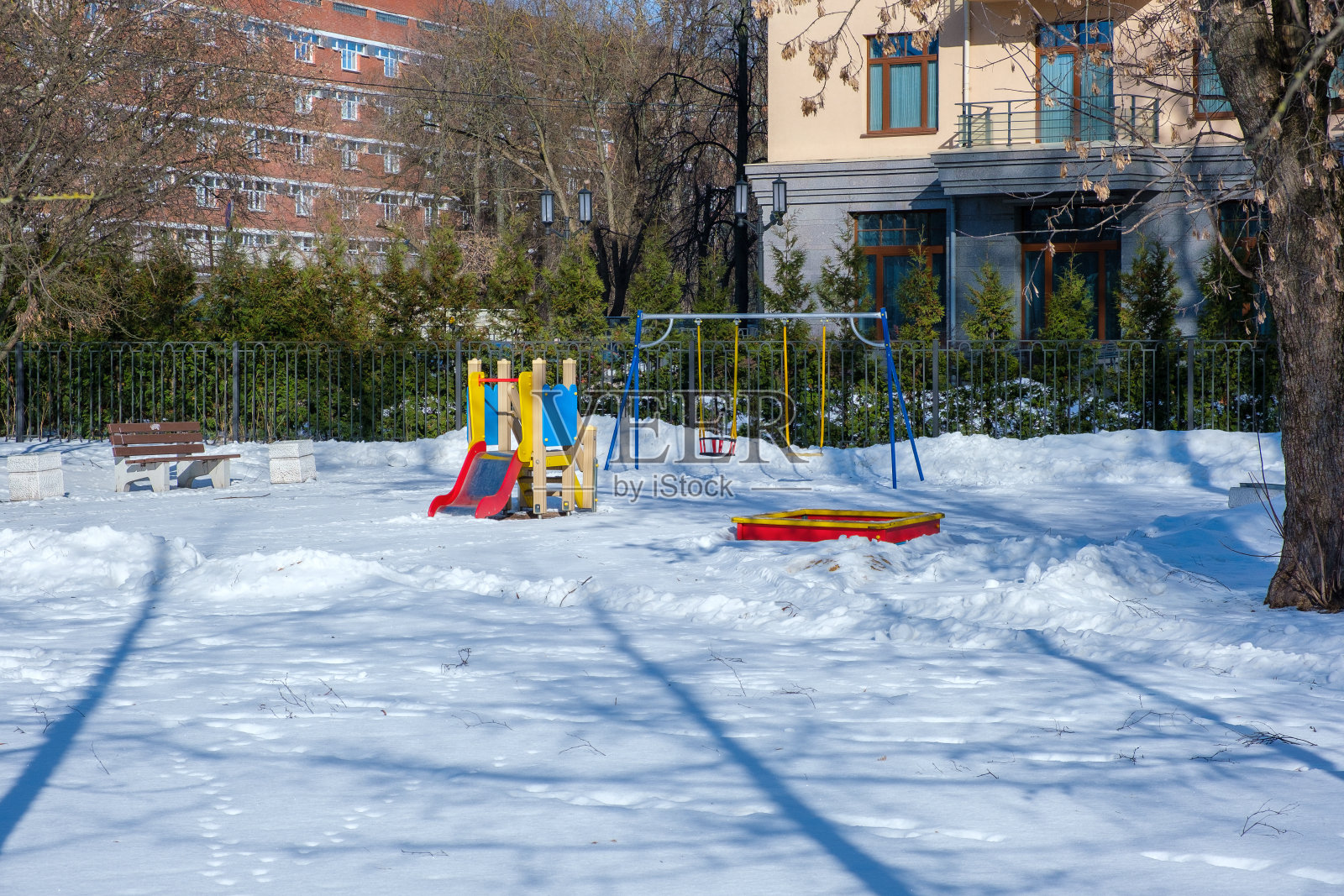 在一个冬日阳光明媚的日子里，一座现代住宅附近的游乐场照片摄影图片