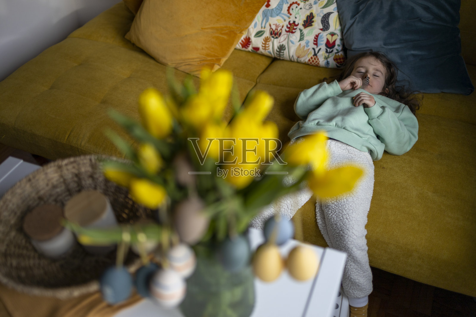 装饰完复活节圣诞树后，疲惫的小女孩睡在黄色沙发上照片摄影图片