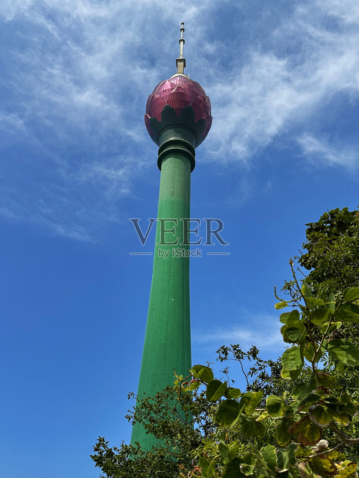 特写图像的绿色茎和粉红色花瓣形状的科伦坡莲花塔，斯里兰卡，通信塔旅游地标，多云的天空背景，从下面看照片摄影图片