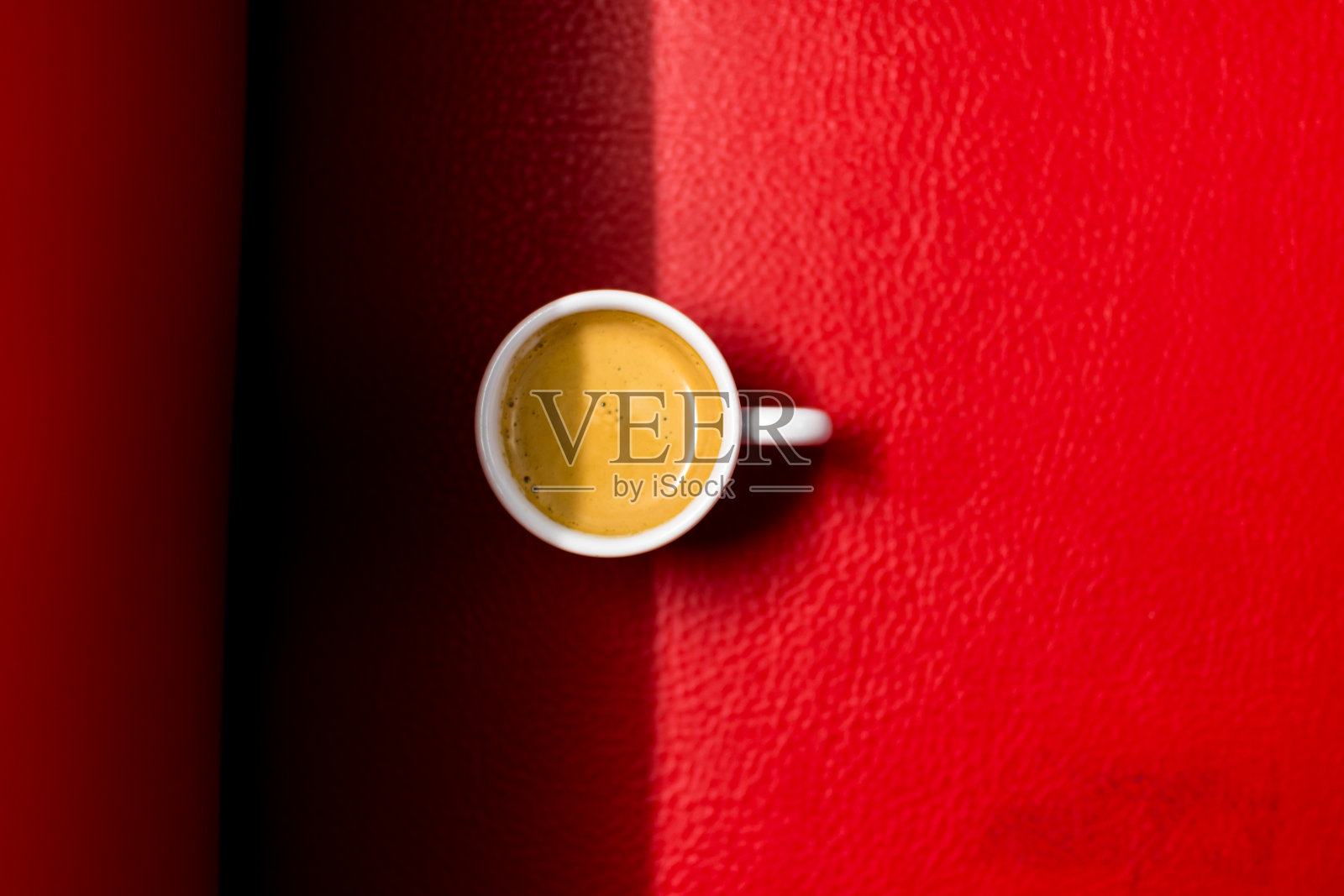 红色皮沙发上放着一个浓缩咖啡杯照片摄影图片