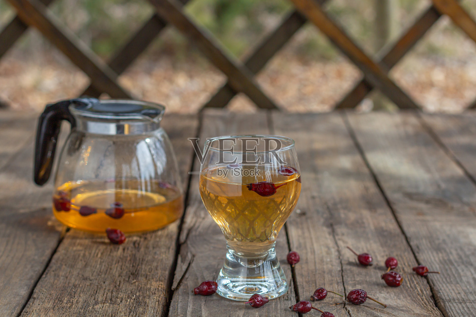 木桌上的透明杯里盛着红茶，玫瑰果茶，乡村风味照片摄影图片