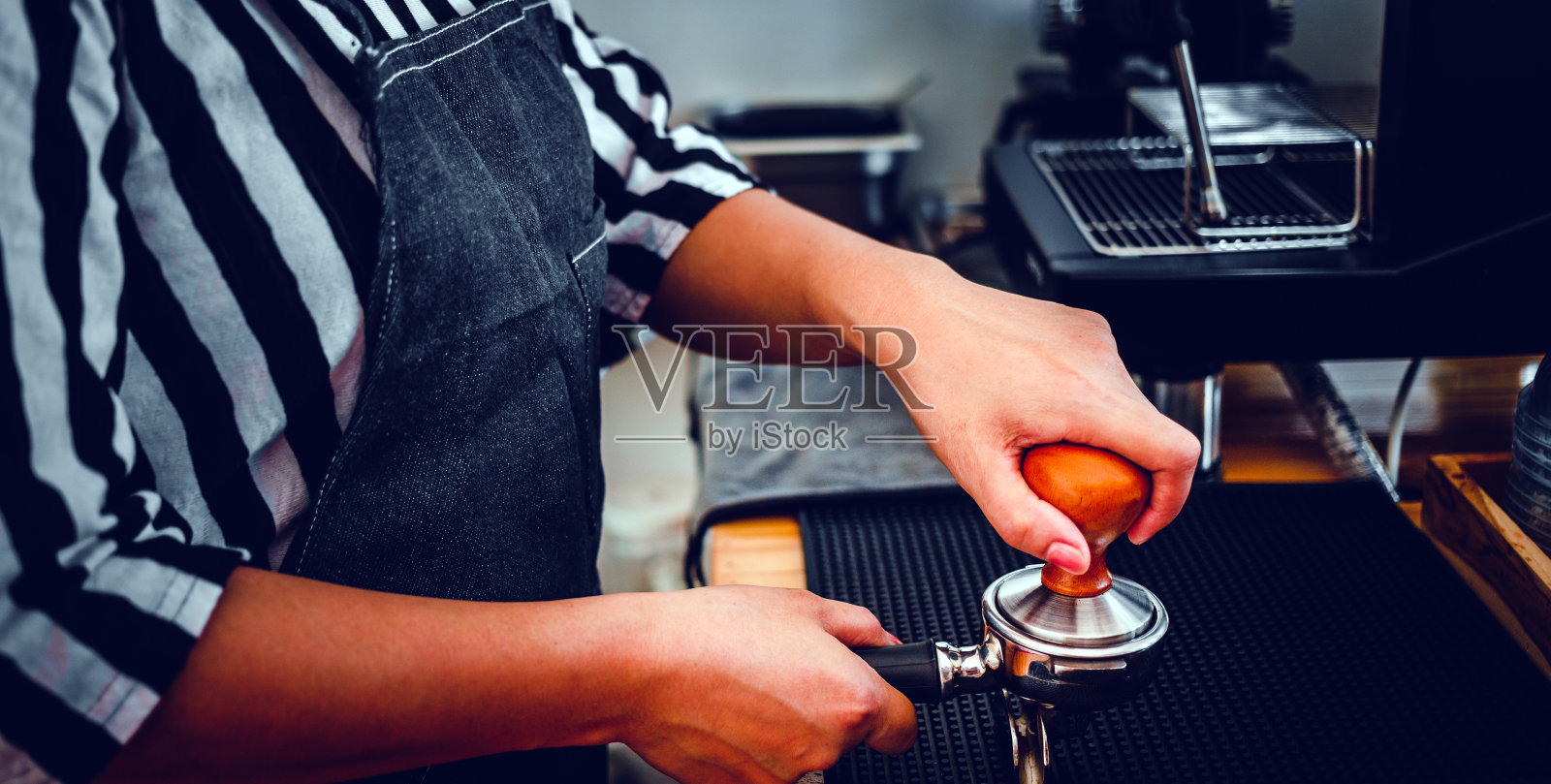 咖啡师拿着便携式过滤器和咖啡捣碎机在咖啡馆里制作浓缩咖啡照片摄影图片