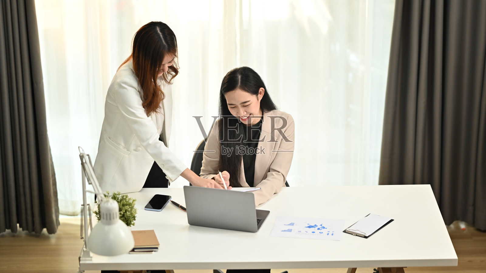 两个快乐的年轻员工在共同办公空间讨论网上信息，分享新创业项目的想法。照片摄影图片