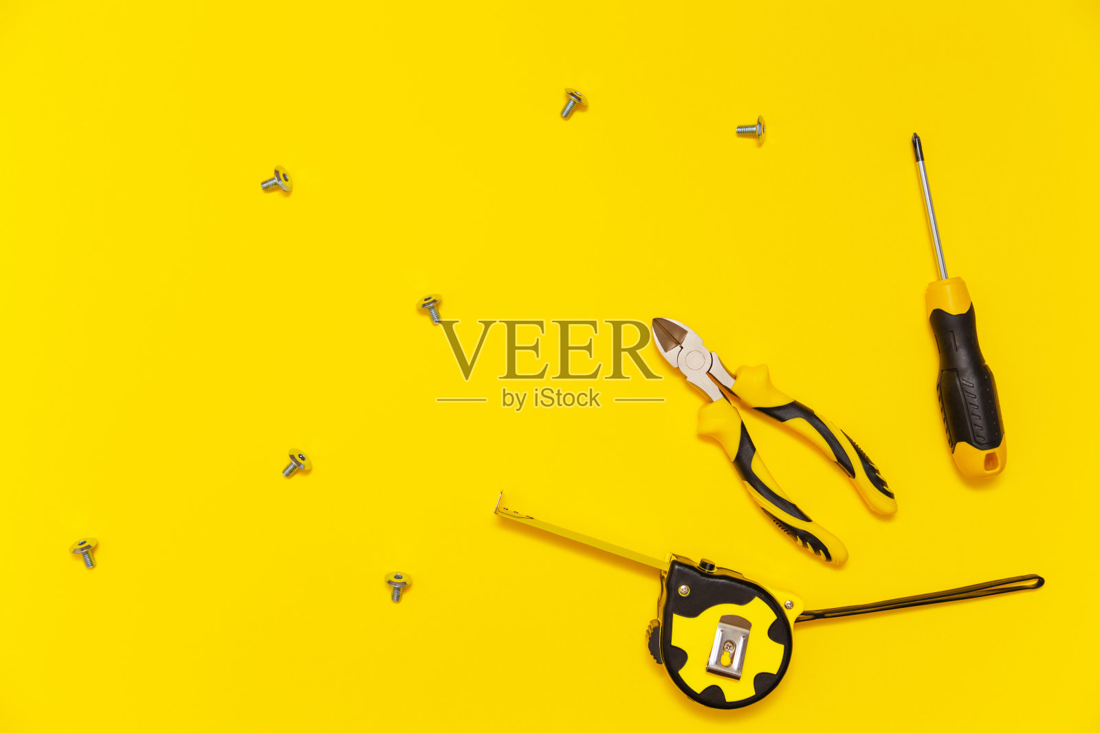 一套工作台工具，螺丝刀，剪钳，卷尺和螺丝在黄色背景，平铺。照片摄影图片