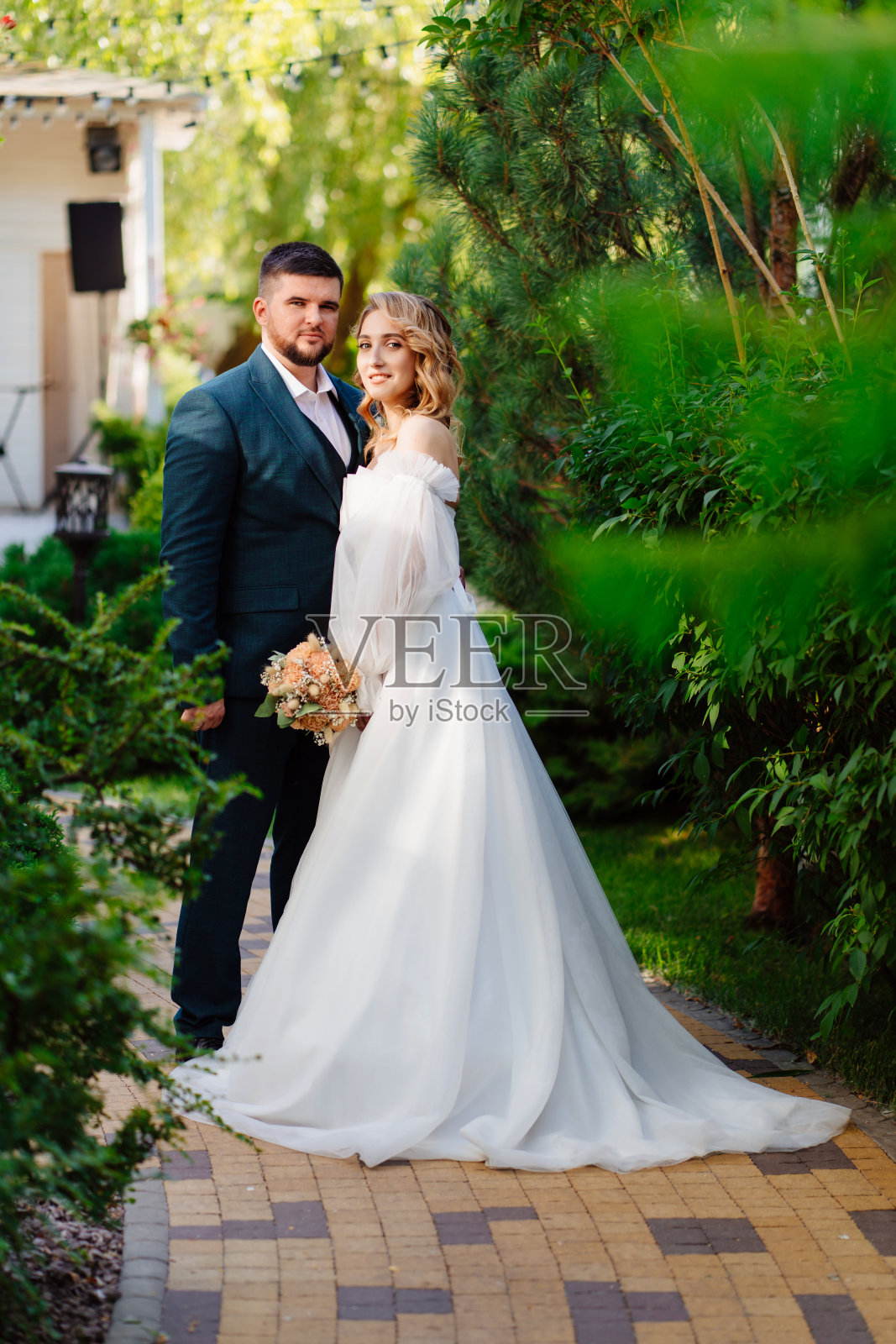 美丽而时尚的新娘和新郎在公园的小路上。照片摄影图片