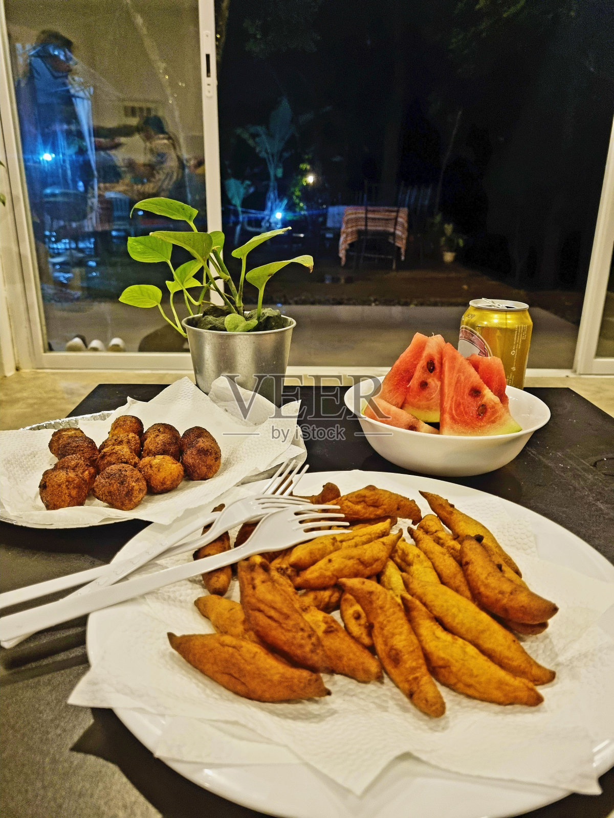 夜宵有鱿鱼丸子(类似于饭团，但有鱿鱼味的丸子)、kikiam(用豆腐皮包裹的猪肉碎)、西瓜和调味啤酒照片摄影图片