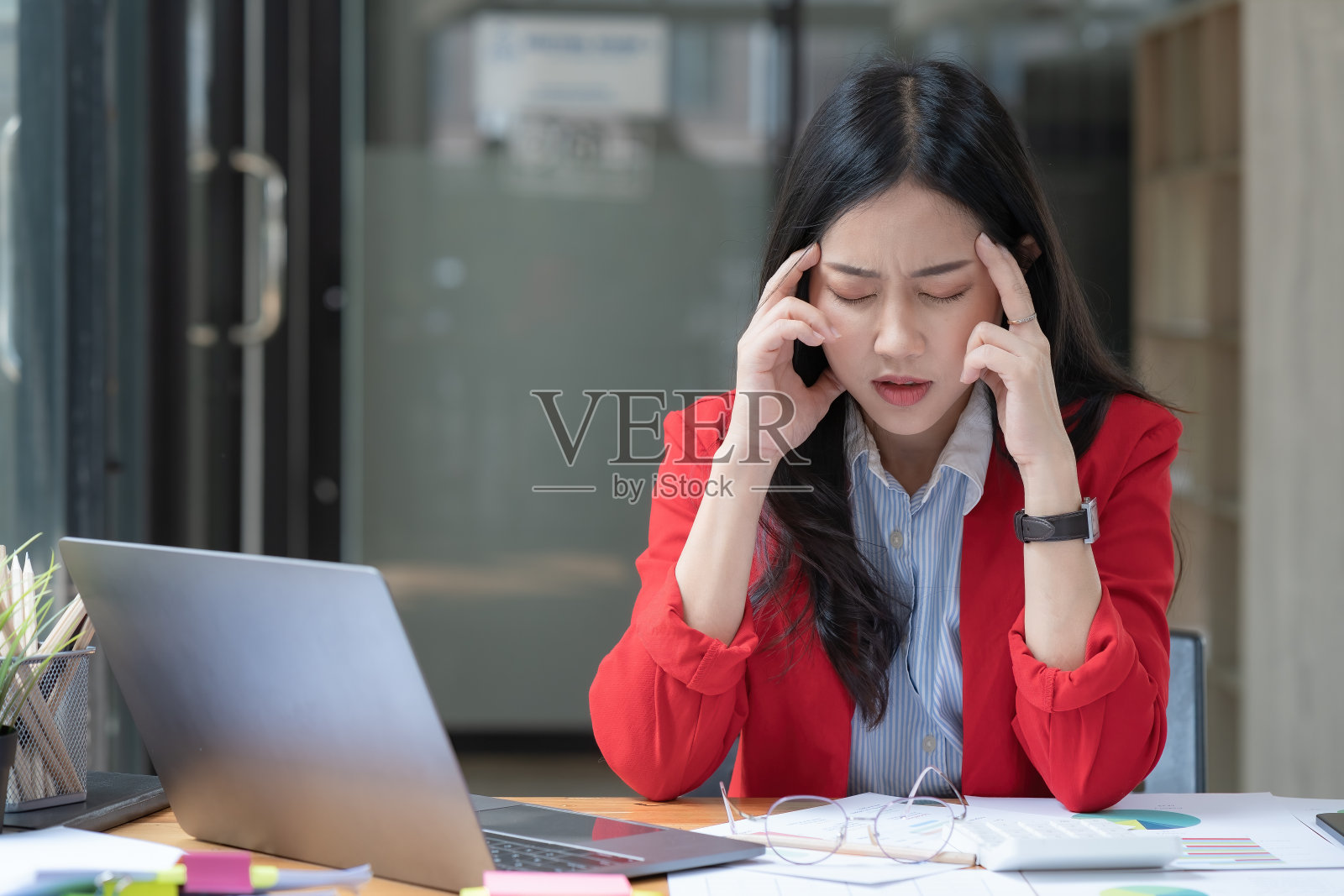 一个亚洲女商人是压力和疲劳的工作坐在办公室的桌子上，在工作中感到恶心，工作压力大。照片摄影图片