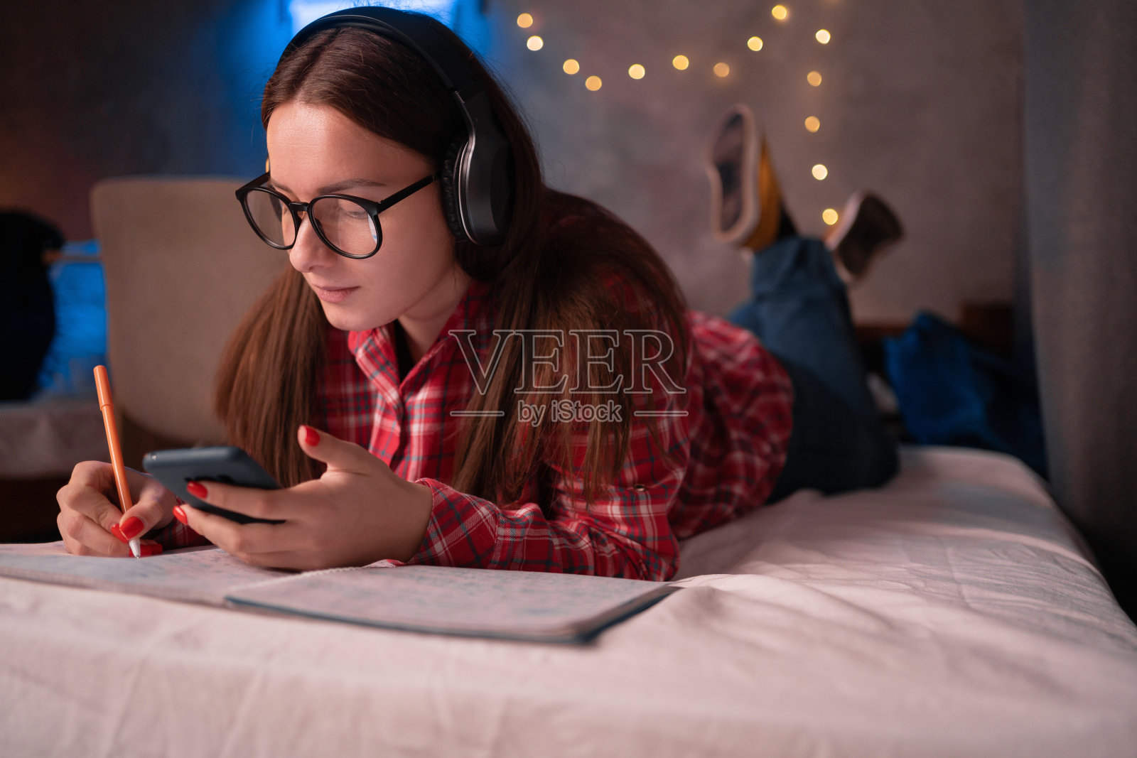 少女学生用手机使用手机应用进行远程学习，在宿舍用app观看在线辅导课程学习照片摄影图片