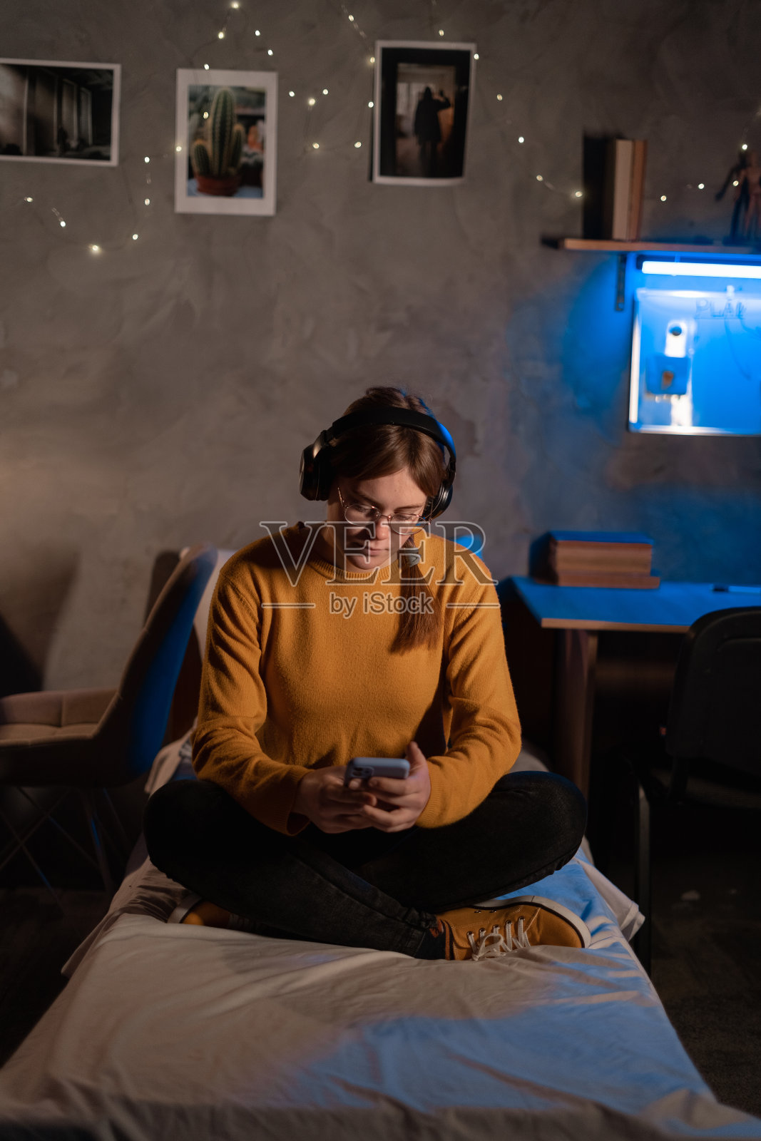 女生坐在宿舍的床上用手机学习。照片摄影图片