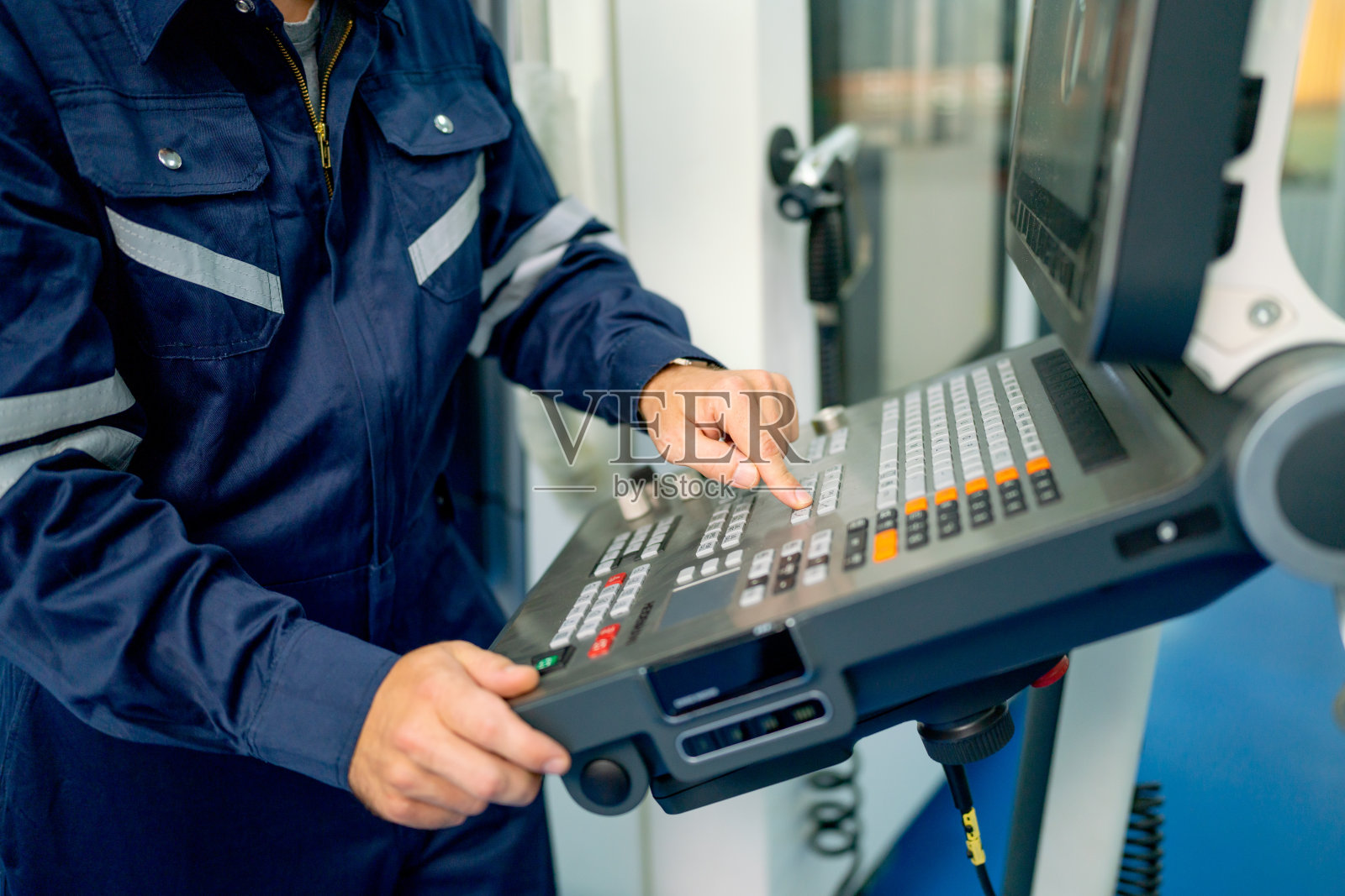 在工厂工作场所，工程师或技术工人双手合拢，按下机器上的按钮。照片摄影图片