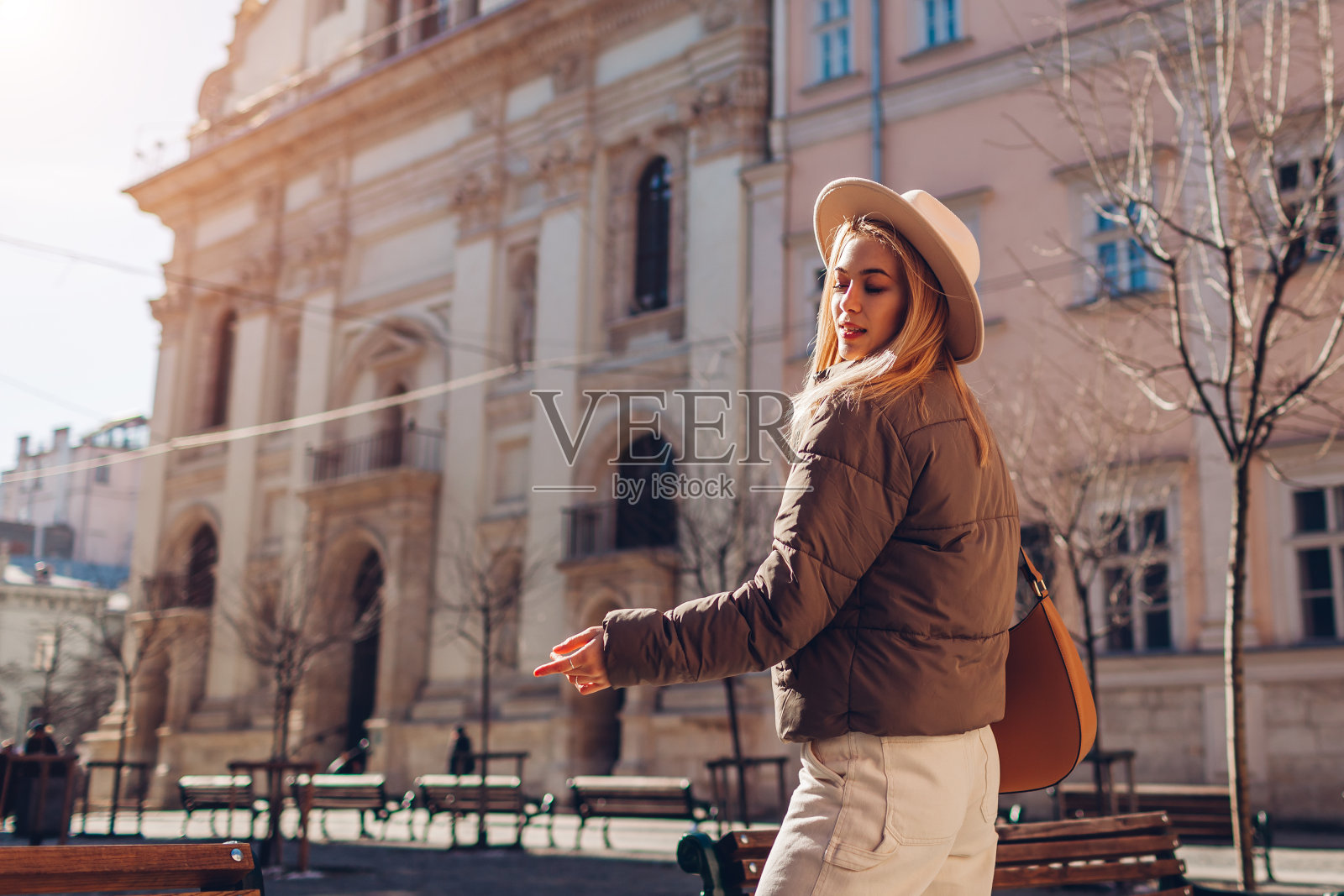 时髦的年轻女子走在欧洲城市的街道上，戴着时髦的帽子和夹克。春季时装照片摄影图片