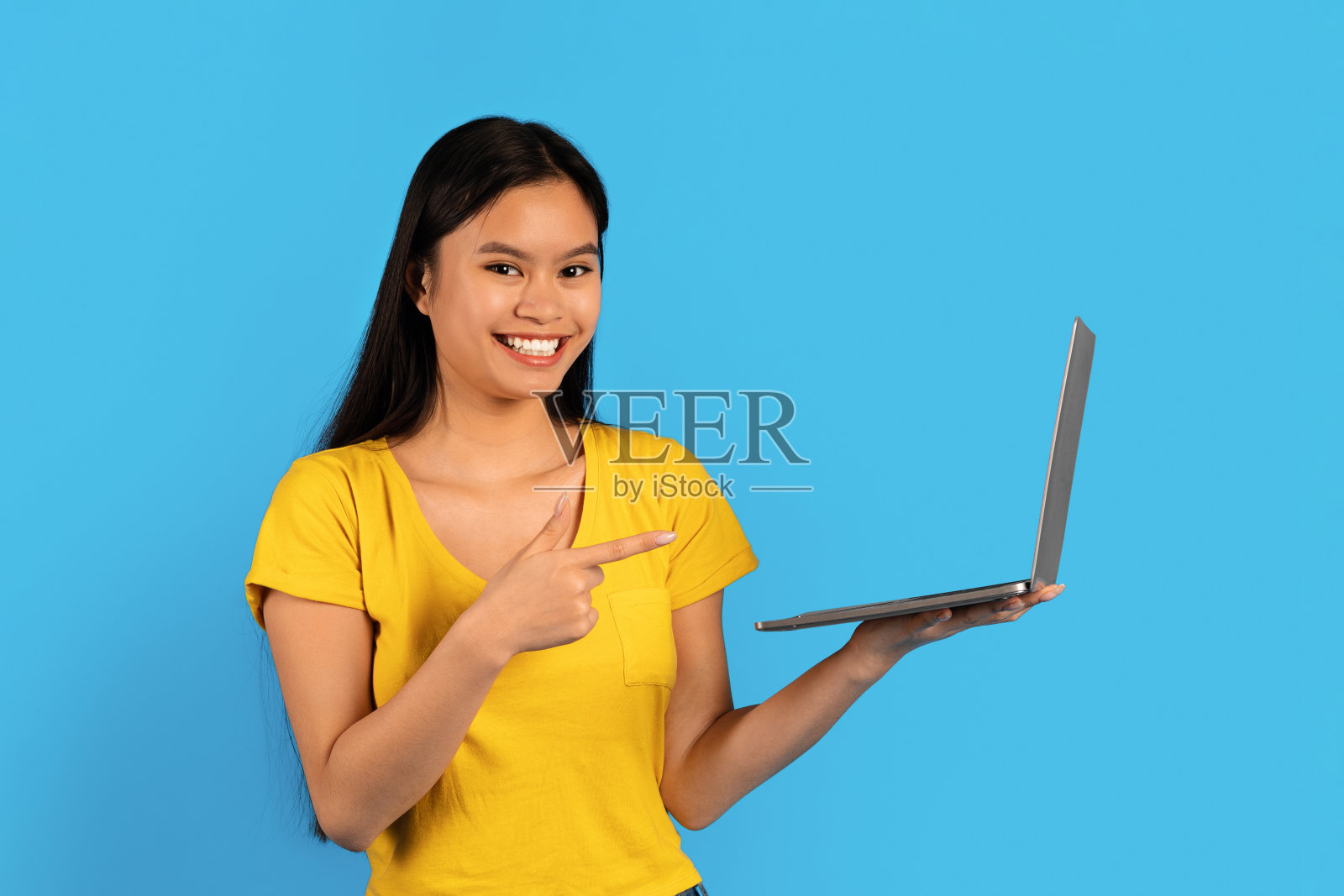 网站推荐，广告和提供。穿着黄色t恤的年轻中国女性微笑着指着笔记本电脑照片摄影图片