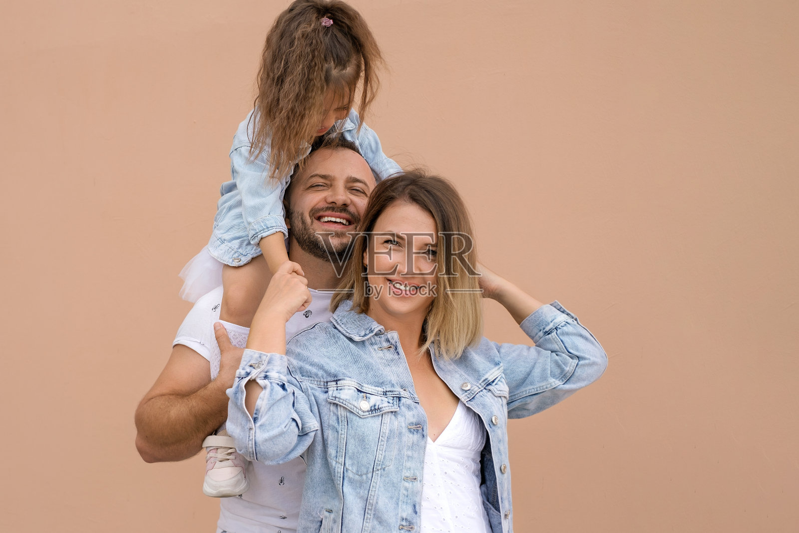 一个快乐的年轻家庭，带着一个小孩子，真诚地笑着。照片摄影图片