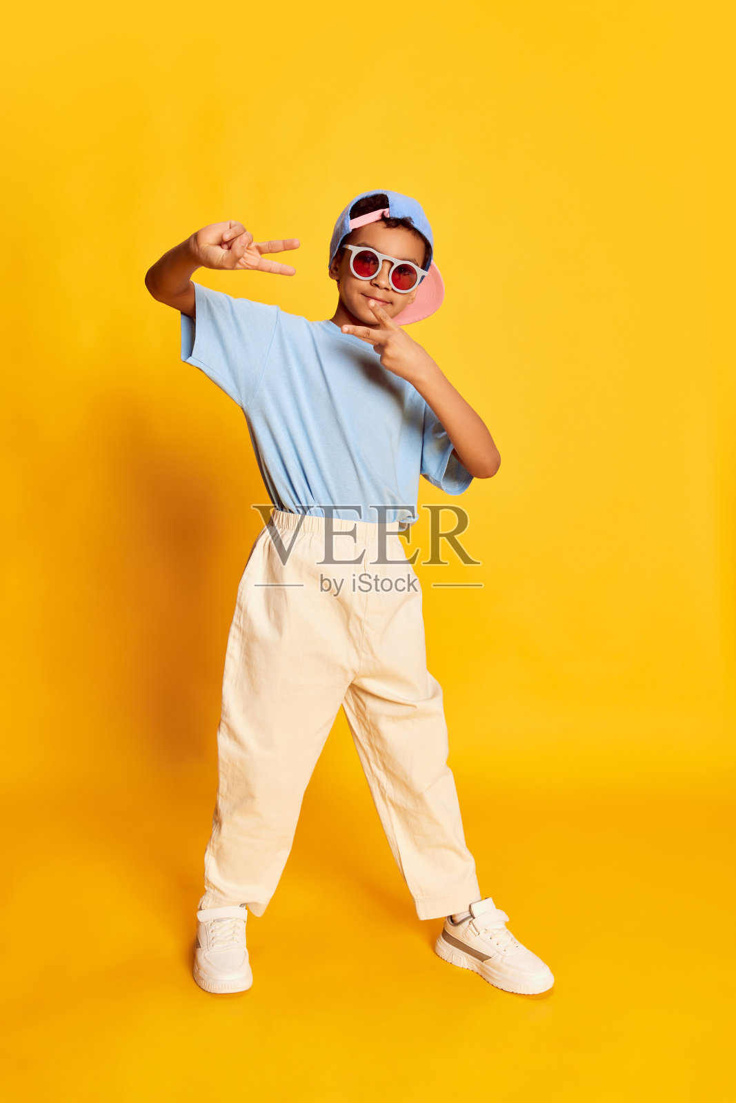 动态的肖像小非洲男孩，嘻哈舞者在时尚街头风格的衣服跳舞在明亮的黄色背景。观念音乐，舞蹈幸福照片摄影图片