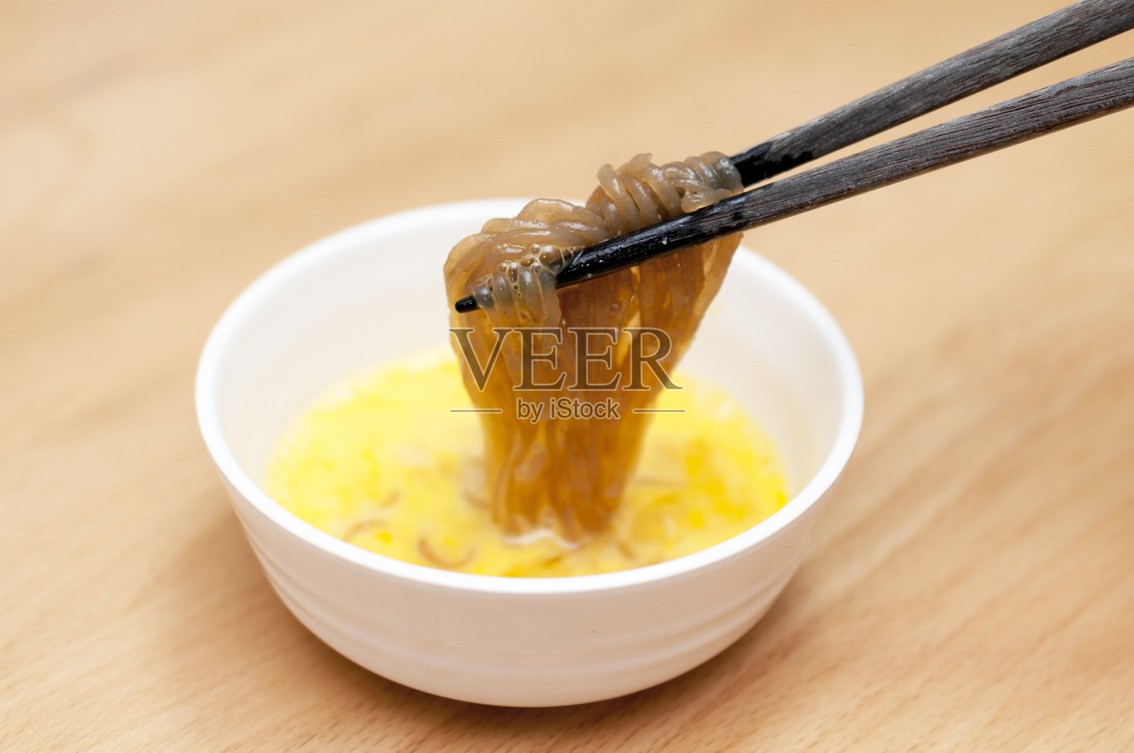 甜辣煮魔芋面浸在生鸡蛋里。照片摄影图片