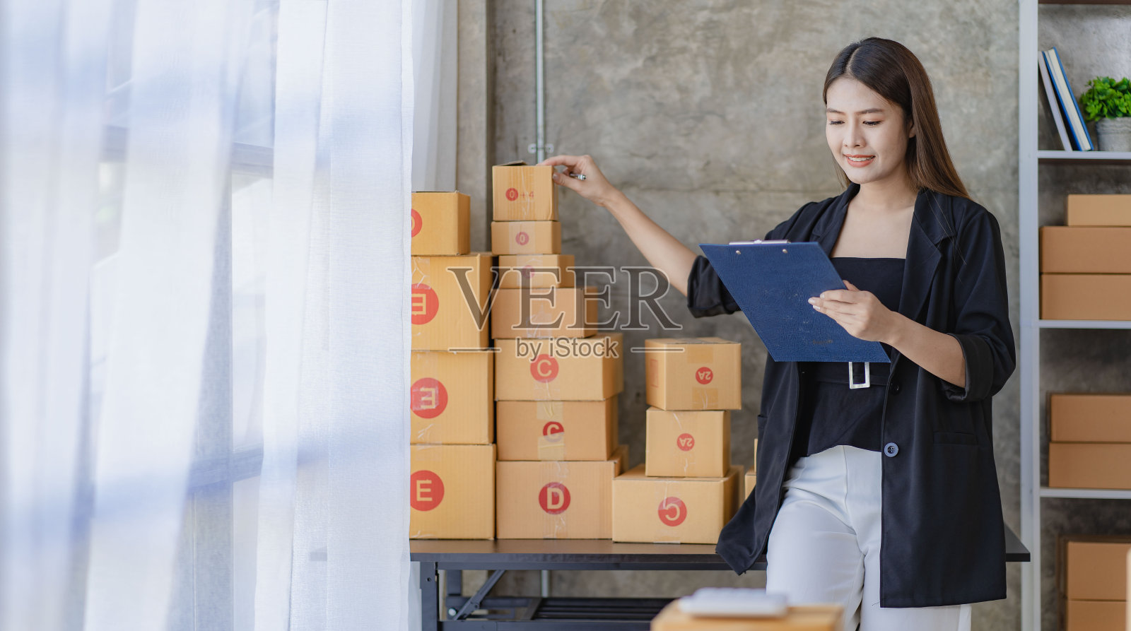 亚洲年轻女性在家工作，检查订单和准备递送包裹，中小企业在线业务概念照片摄影图片