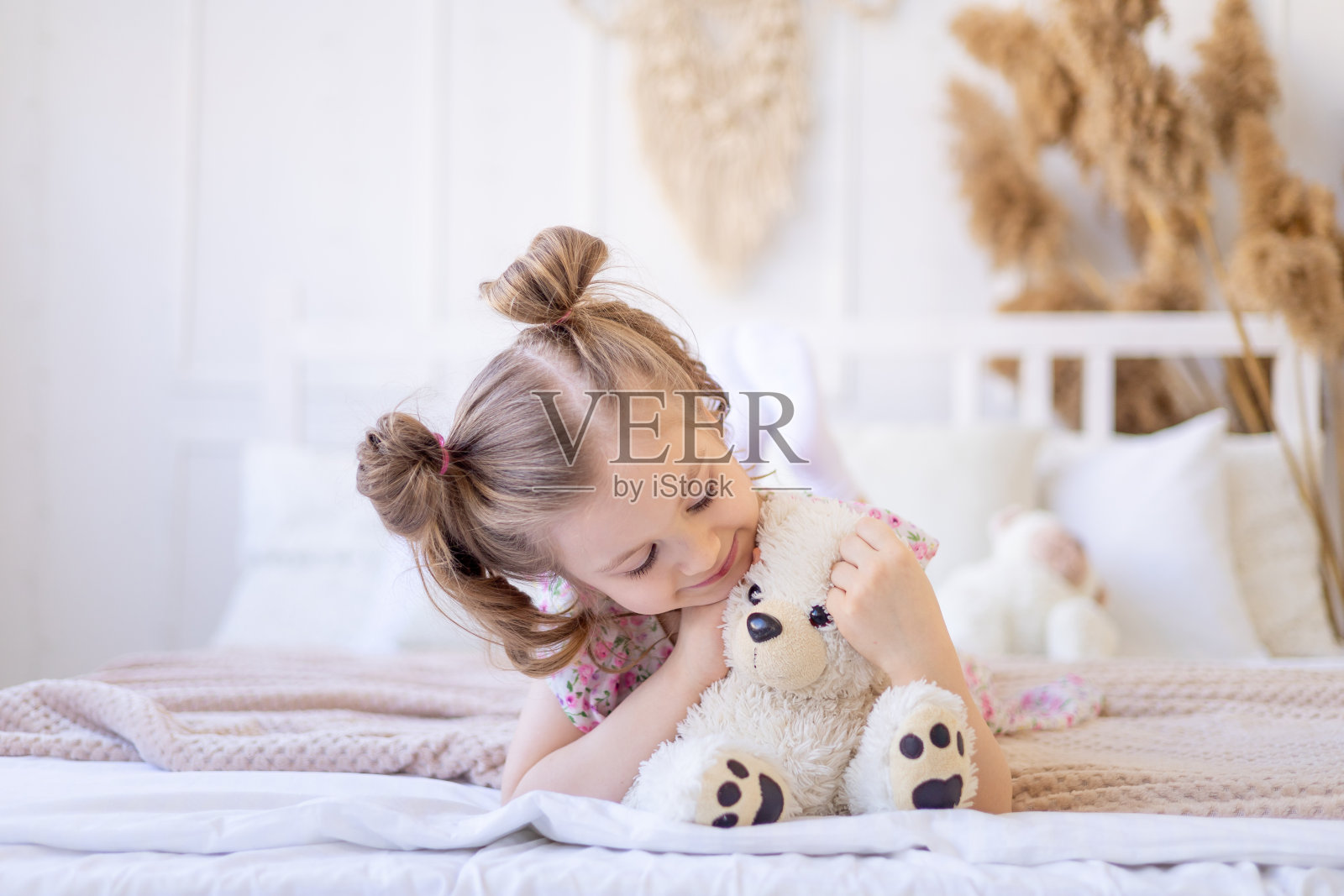 一个小女孩在米色的平静自然的室内玩耍，抱着一只柔软的泰迪熊照片摄影图片