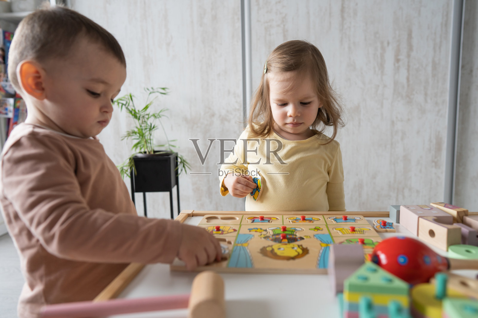两个蹒跚学步的孩子，一个男孩和一个女孩在家里玩木制玩具，蒙特梭利儿童，早期儿童发展和学习概念照片摄影图片