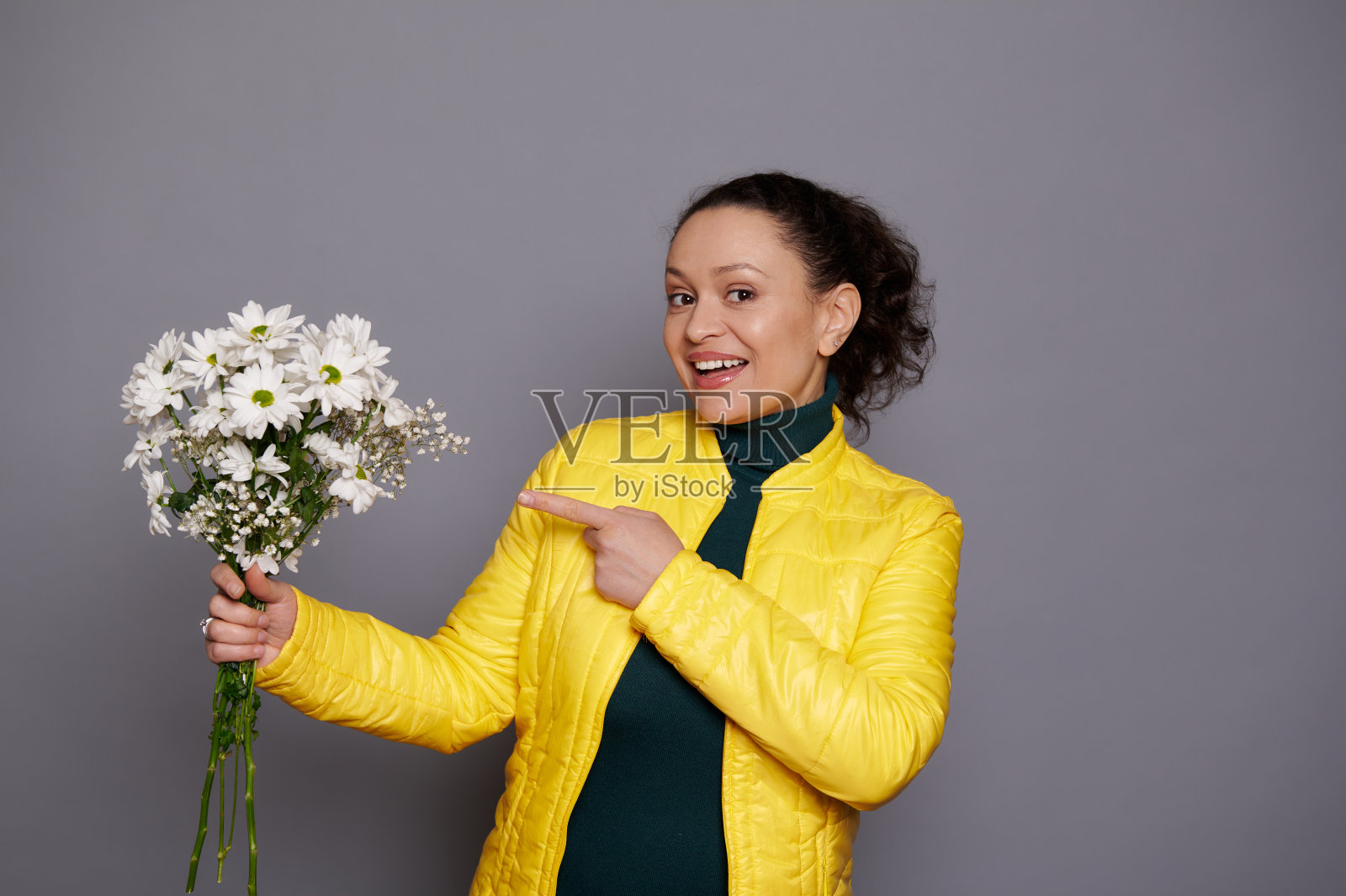 微笑的女人展示了一束美丽的白色菊花为妇女，母亲节或任何节日，灰色背景照片摄影图片