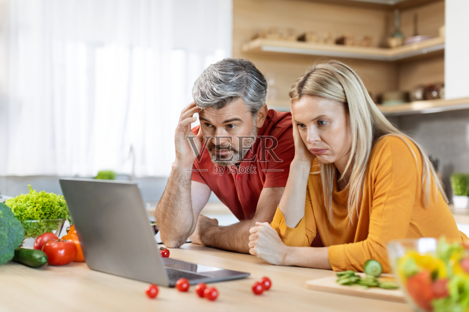 困惑的中年夫妻一起做饭，看美食博客照片摄影图片