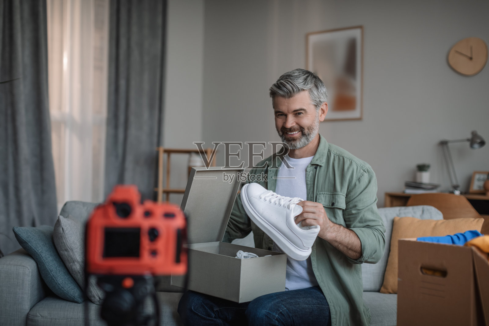 开朗的年长欧洲男性胡须拍摄vlog，评论运动鞋，享受网上购物照片摄影图片