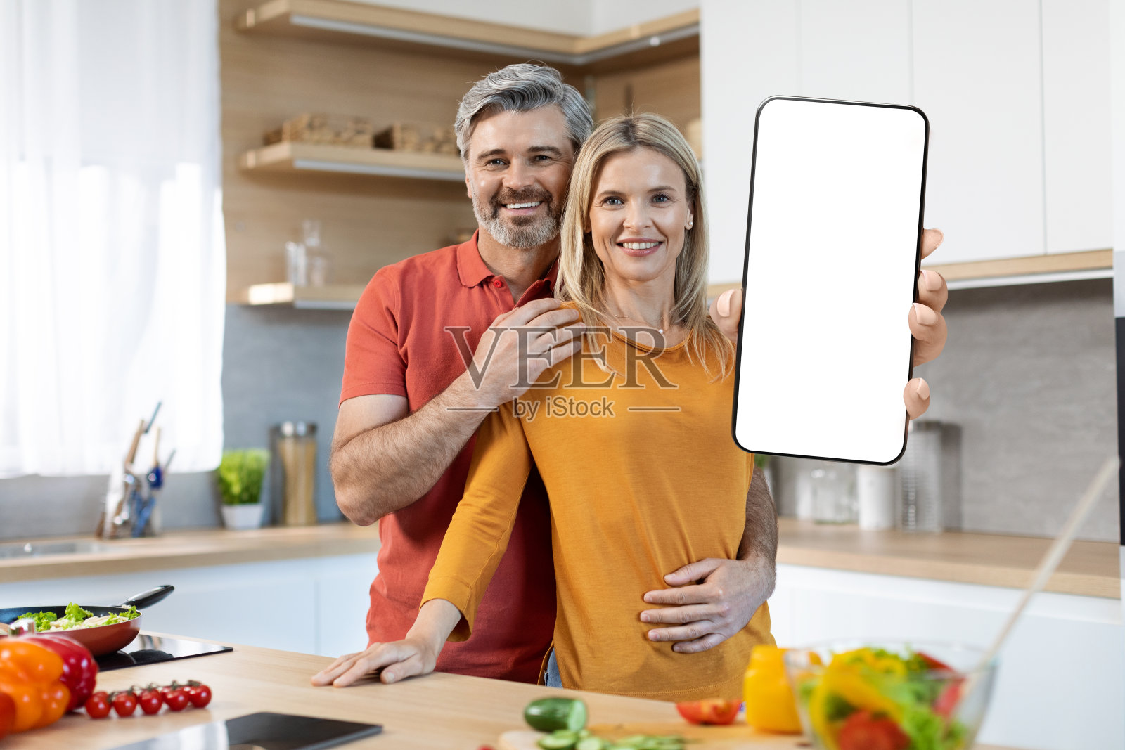 相爱的夫妻一起做饭，展示智能手机，模型照片摄影图片