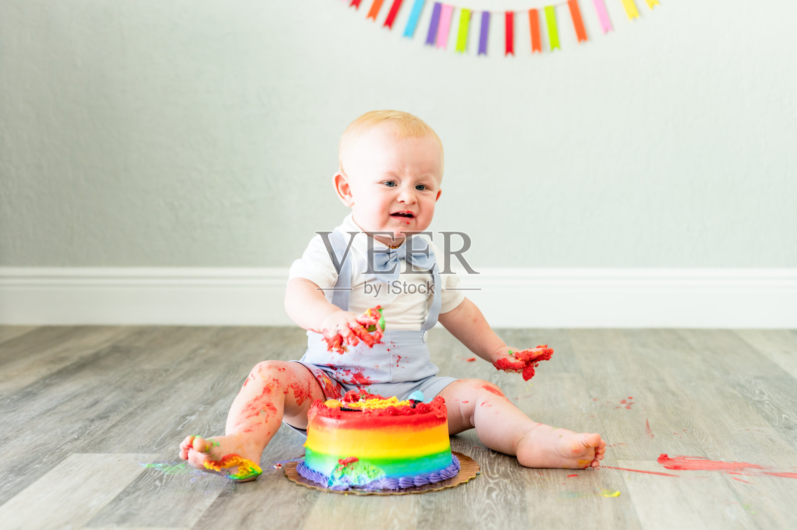 一个小男孩一岁的生日蛋糕，他觉得恶心，非常不确定，有趣的可爱的孩子照片摄影图片