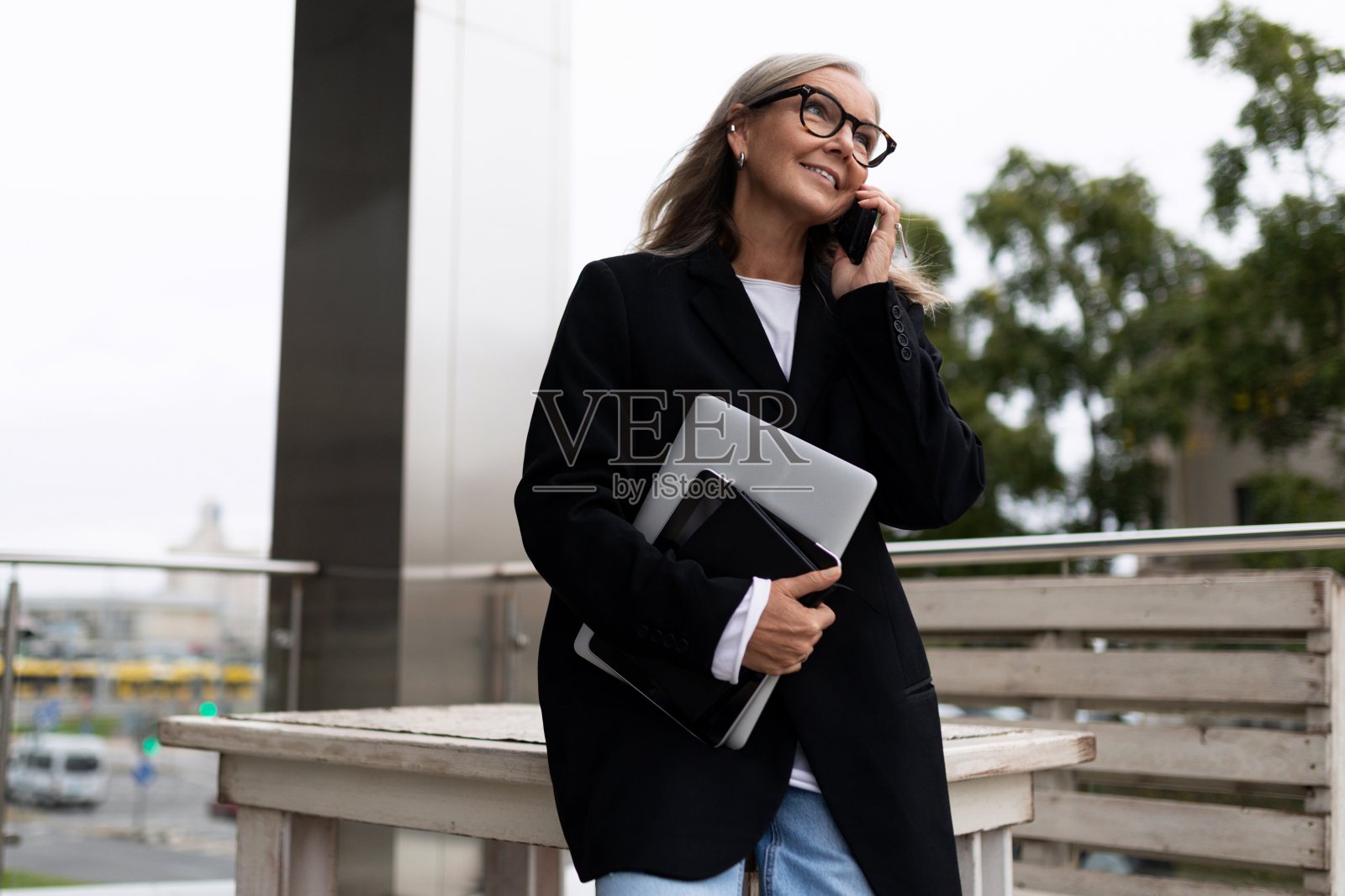 一位成功的商人的肖像，他手里拿着一台笔记本电脑，正在打电话照片摄影图片