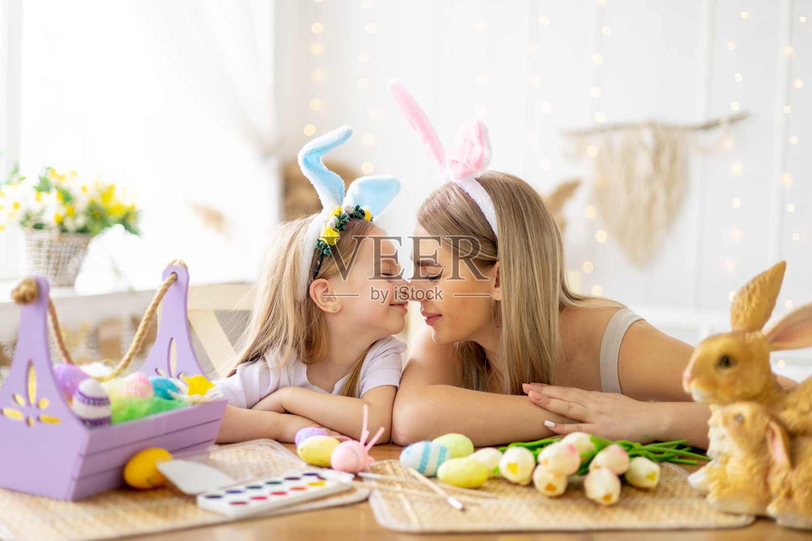 复活节，妈妈和头上戴着兔子耳朵的小女儿正在为假期做准备，他们在一起玩得很开心，花时间在一起，彩色的鸡蛋，生活方式，照片摄影图片