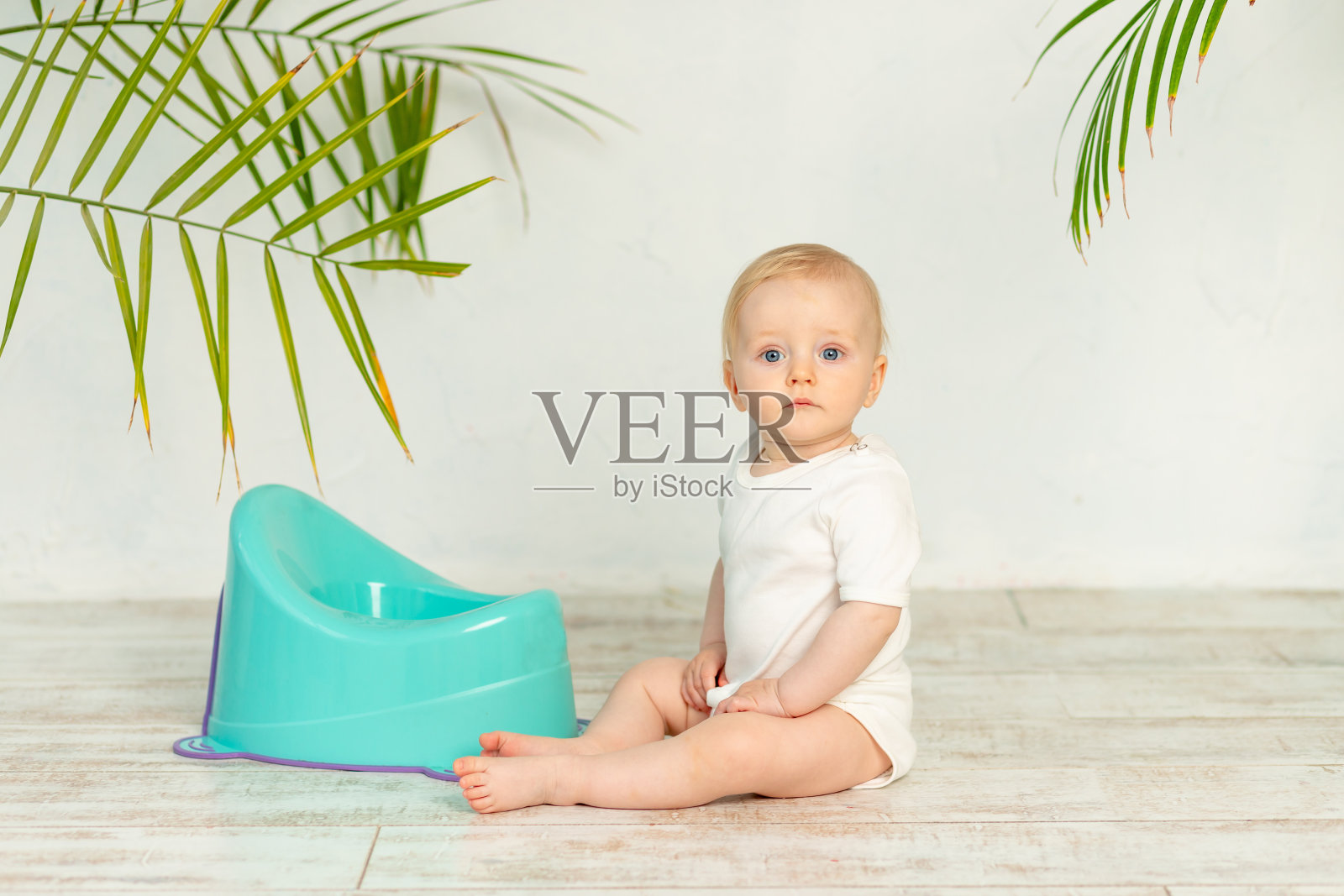 金发小男孩，穿着白色紧身衣，地板上放着一个蓝色的罐子照片摄影图片