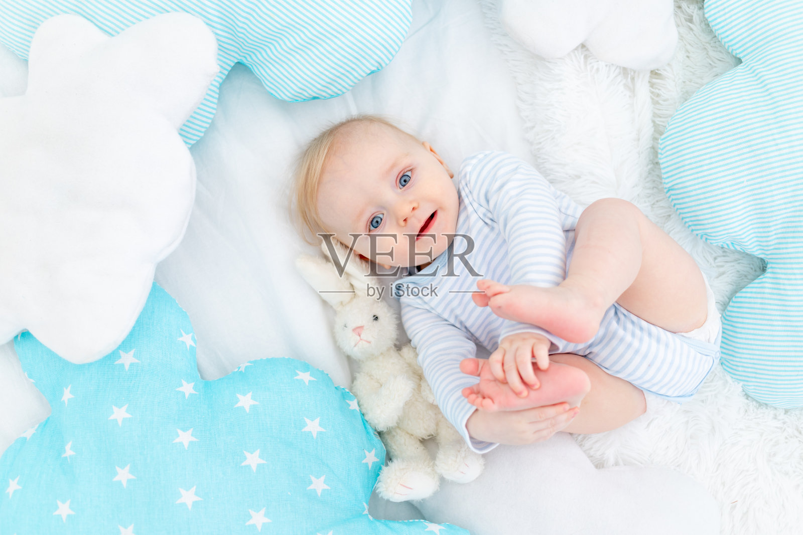 快乐的男婴六个月大，躺在床上的毛绒玩具兔子，可爱的金发宝宝照片摄影图片