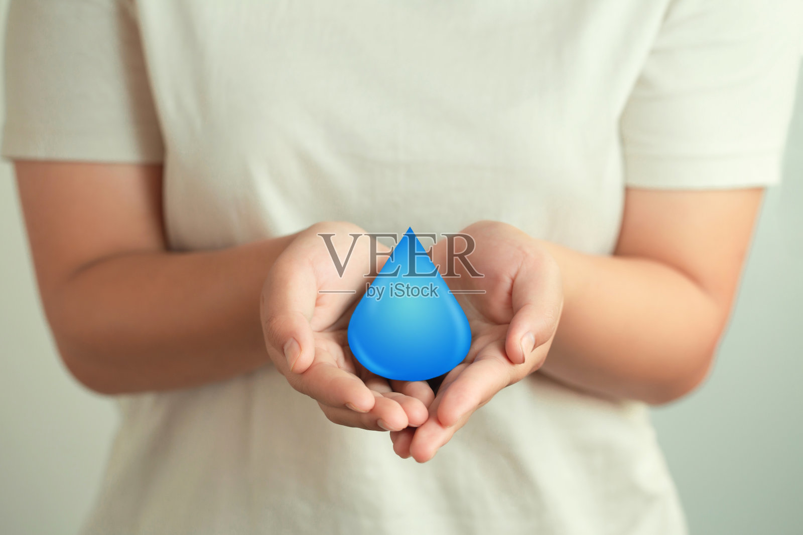 女人手里捧着一滴水，清洁可再生能源。世界水日概念。节约用水与世界环保理念。节约用水，拯救生命。照片摄影图片